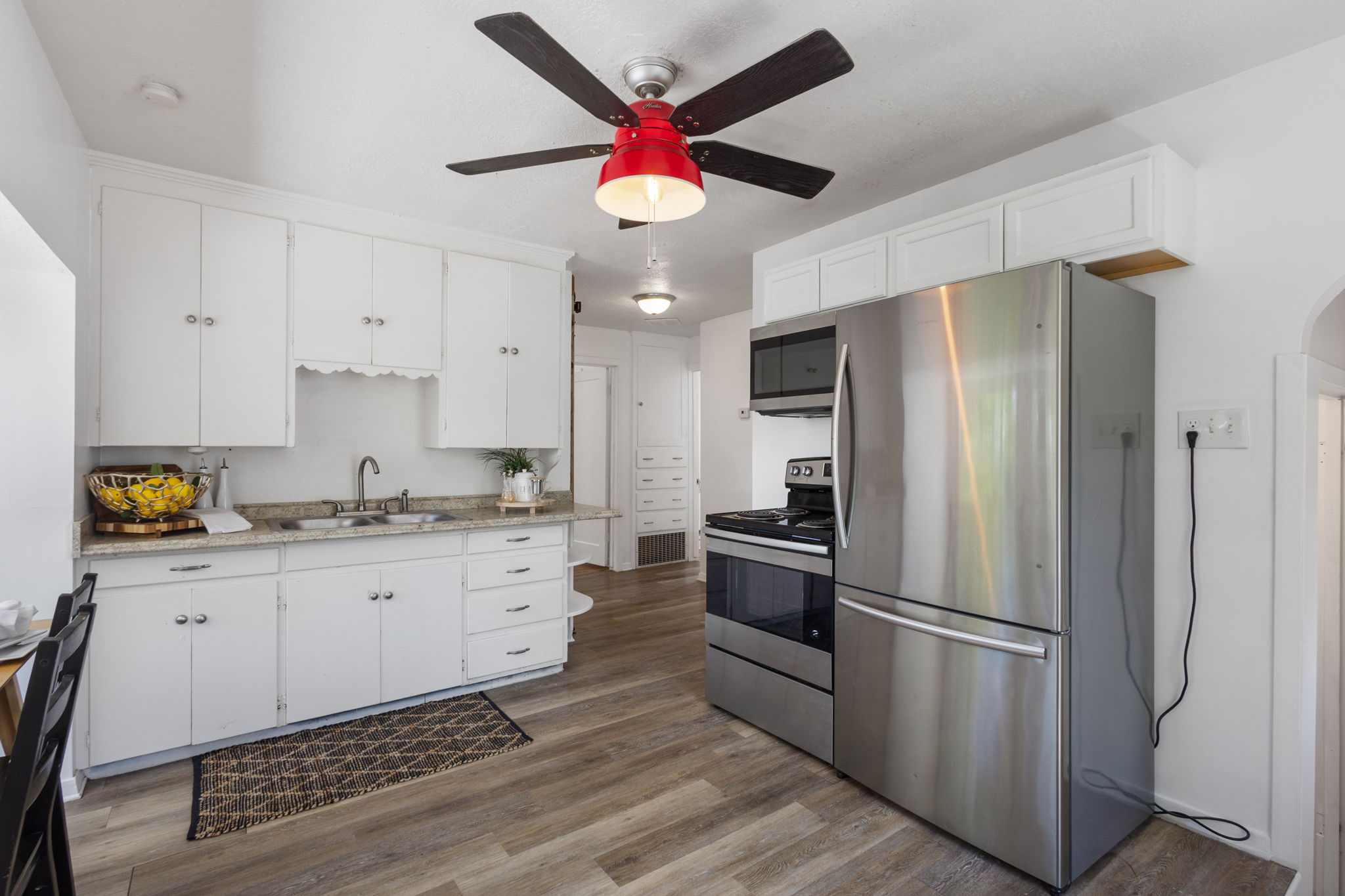 Kitchen featuring LVP flooring, white cabinetry, a stainless steel refrigerator, stainless steel range, and a ceiling fan with light fixture