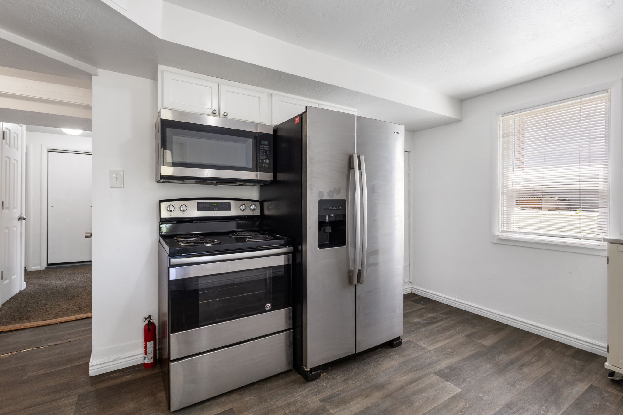 Kitchen area featuring LVP flooring, white cabinetry, and stainless steel appliances including a side-by-side refrigerator, electric range, and built-in microwave