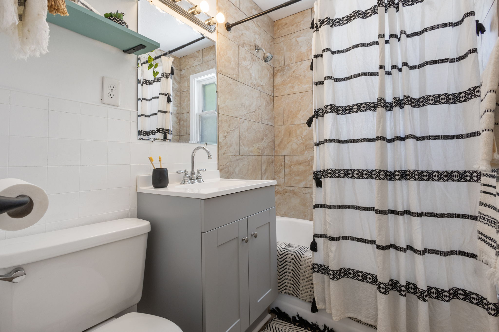 Bathroom featuring a single vanity with a gray cabinet, white countertop, and chrome faucet