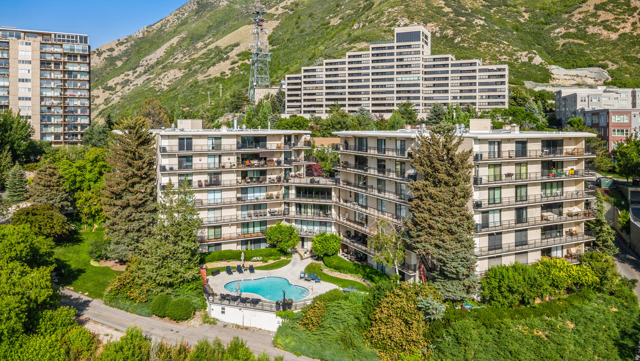 Multi-story residential buildings featuring individual balconies and a prominent central swimming pool