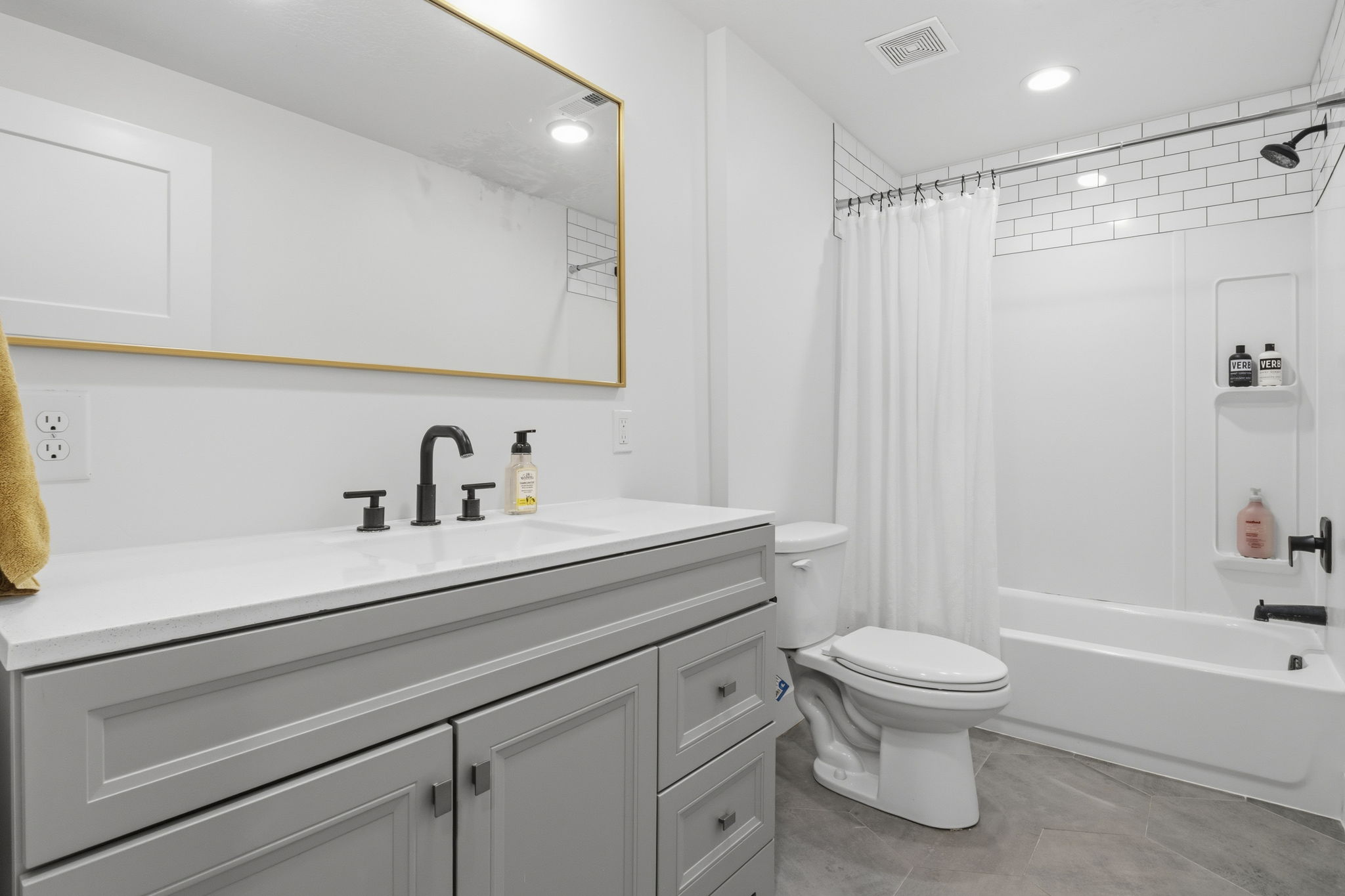 Contemporary bathroom featuring a light gray vanity with a white countertop and matte black fixtures
