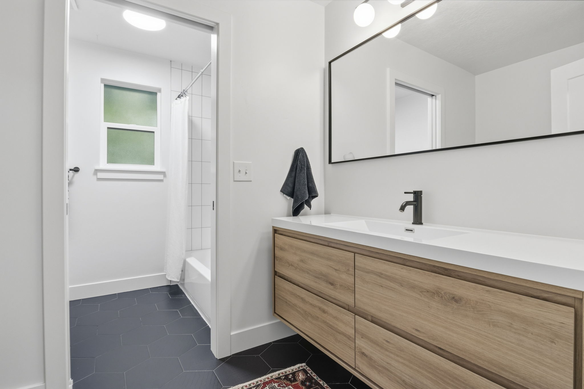 Modern bathroom vanity featuring a light wood-finish with integrated rectangular sink and matte black faucet
