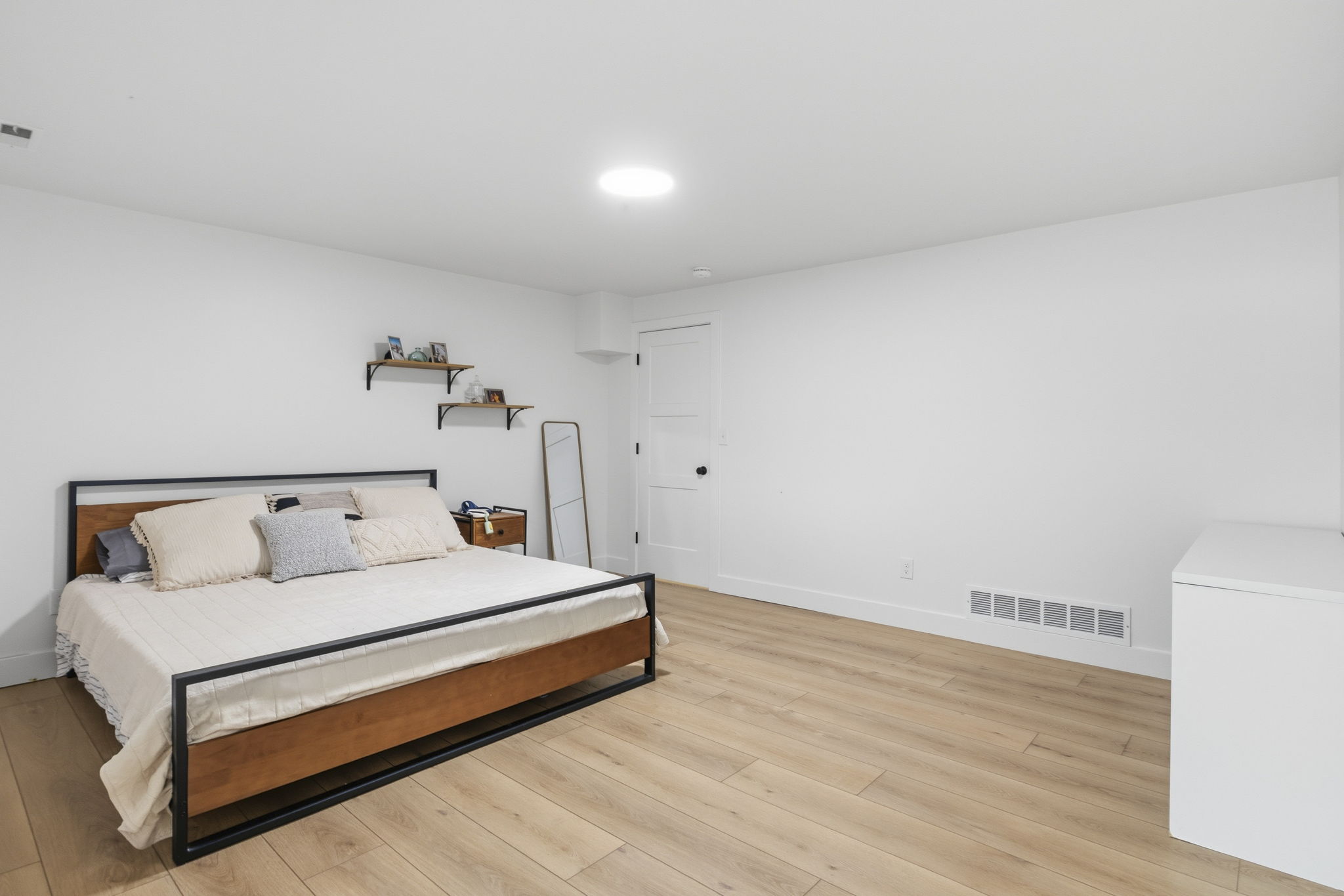 Spacious room featuring light wood-finish flooring, white walls, and a recessed ceiling light