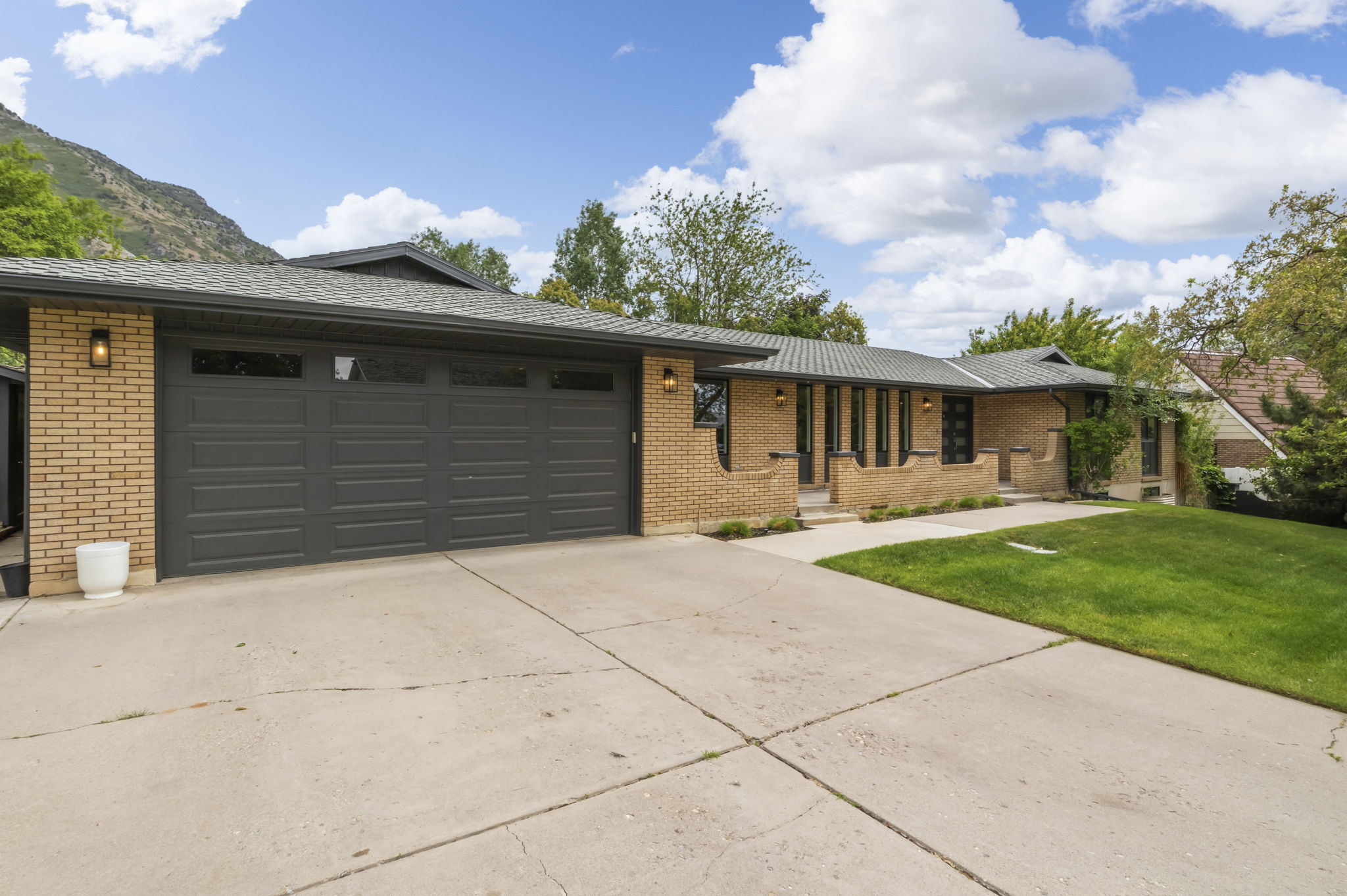 Brick exterior featuring a multi-car garage, concrete driveway, and front lawn