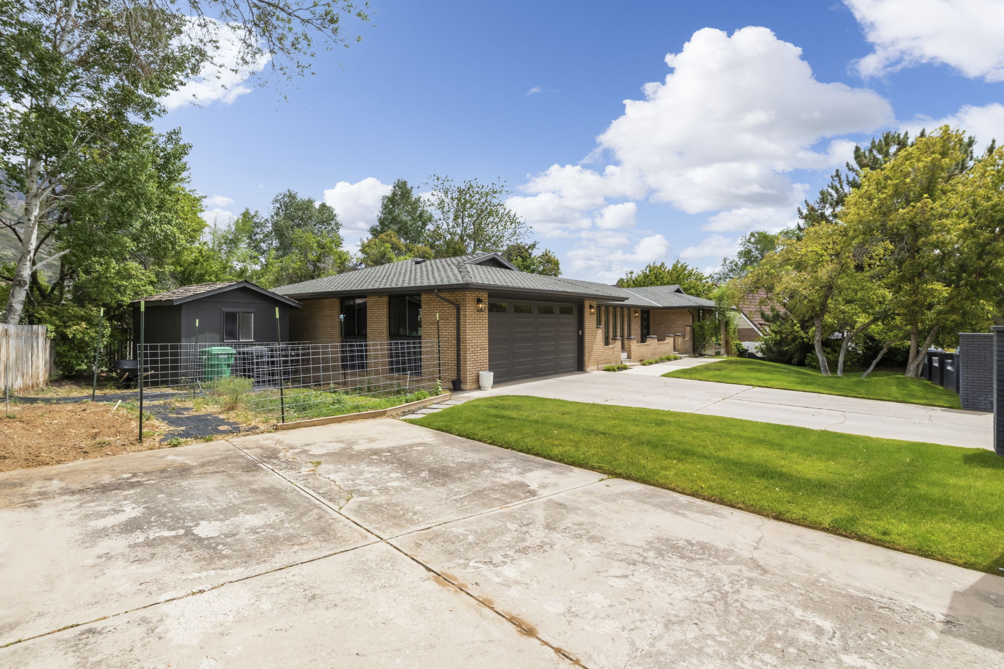 Brick exterior with an attached garage, featuring a concrete driveway and a grassy front lawn