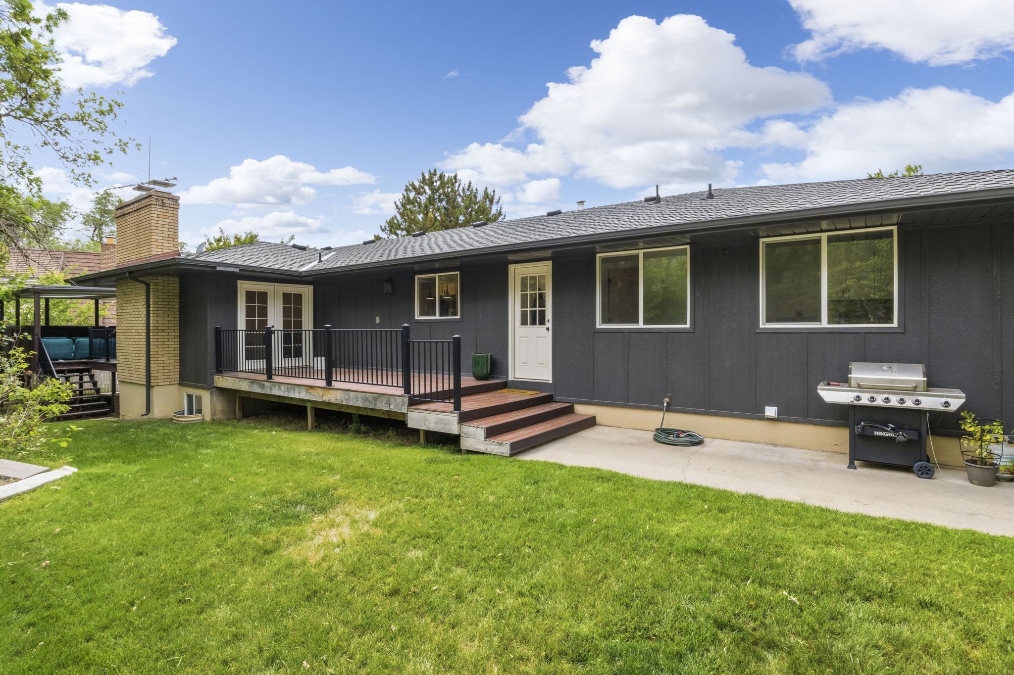 Expansive green lawn bordering a multi-level deck with dark railings and a secondary covered patio