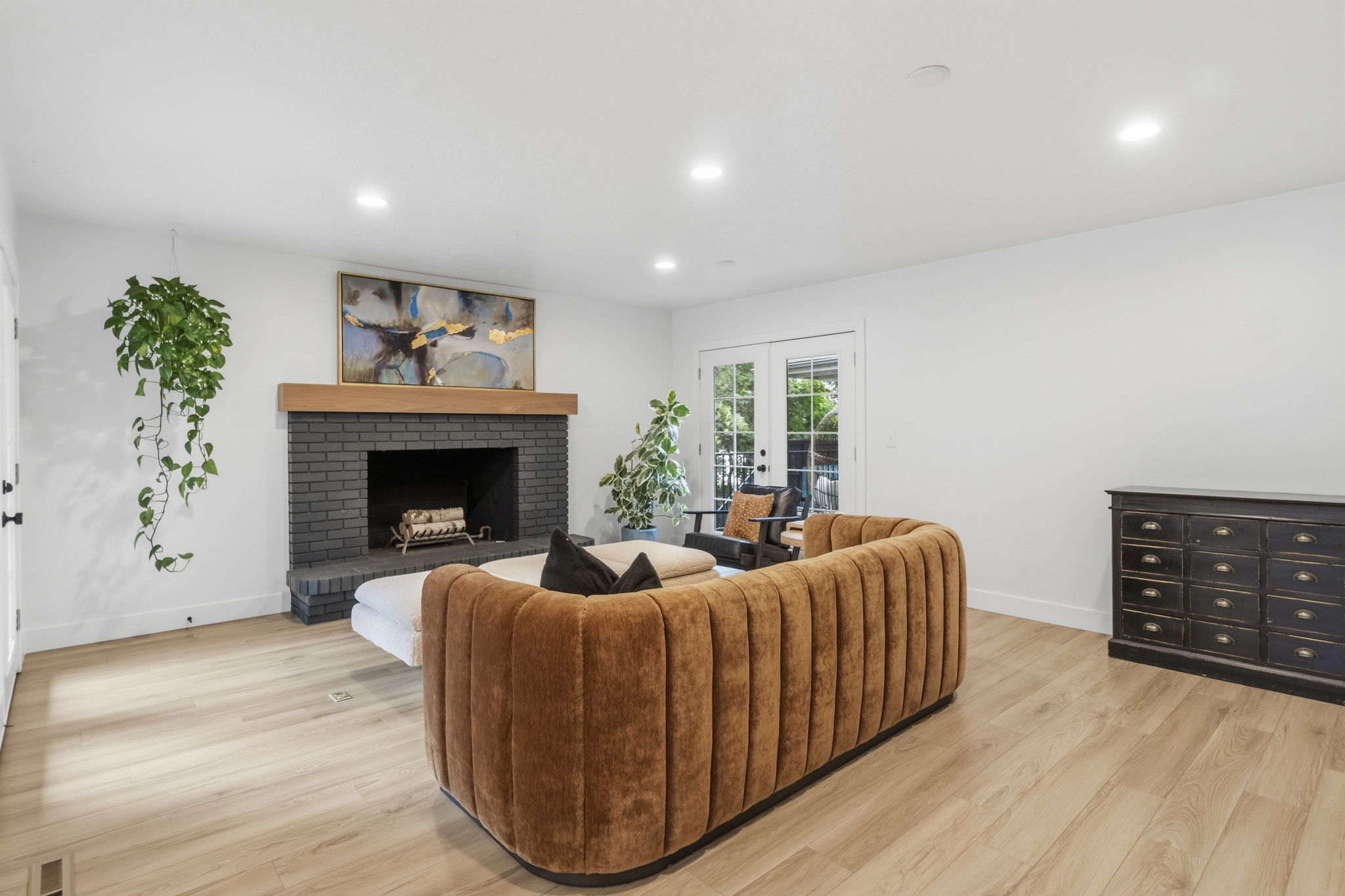 Living area featuring a dark brick fireplace with a wood mantel, light wood-finish flooring, recessed lighting, and white walls