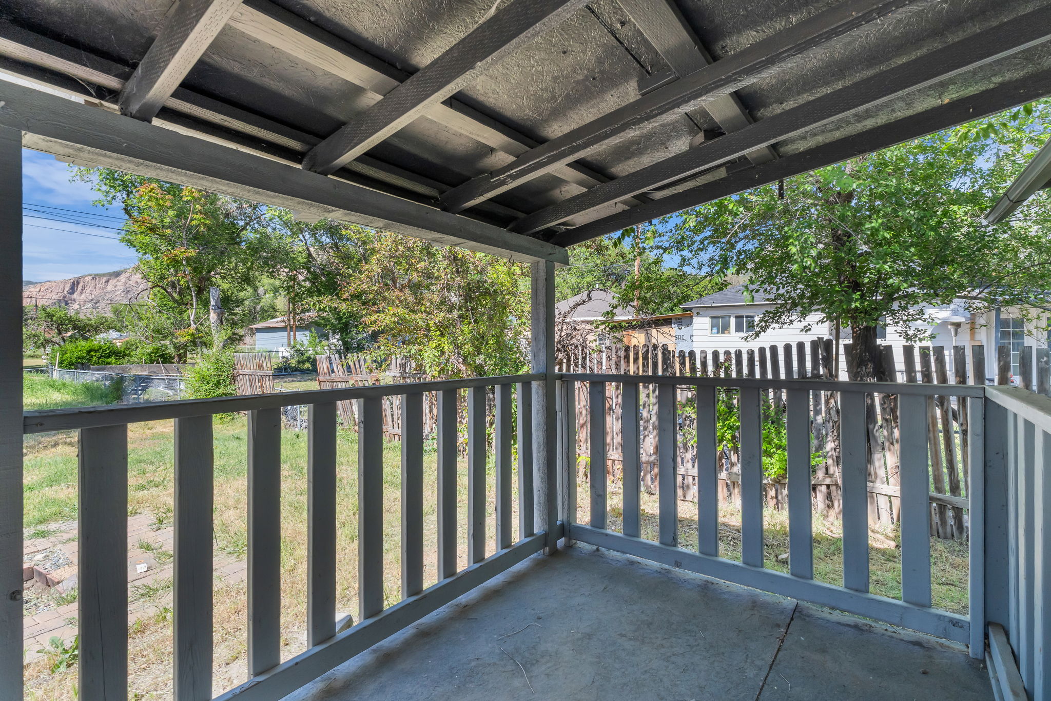 Covered porch with painted wood railing and concrete flooring