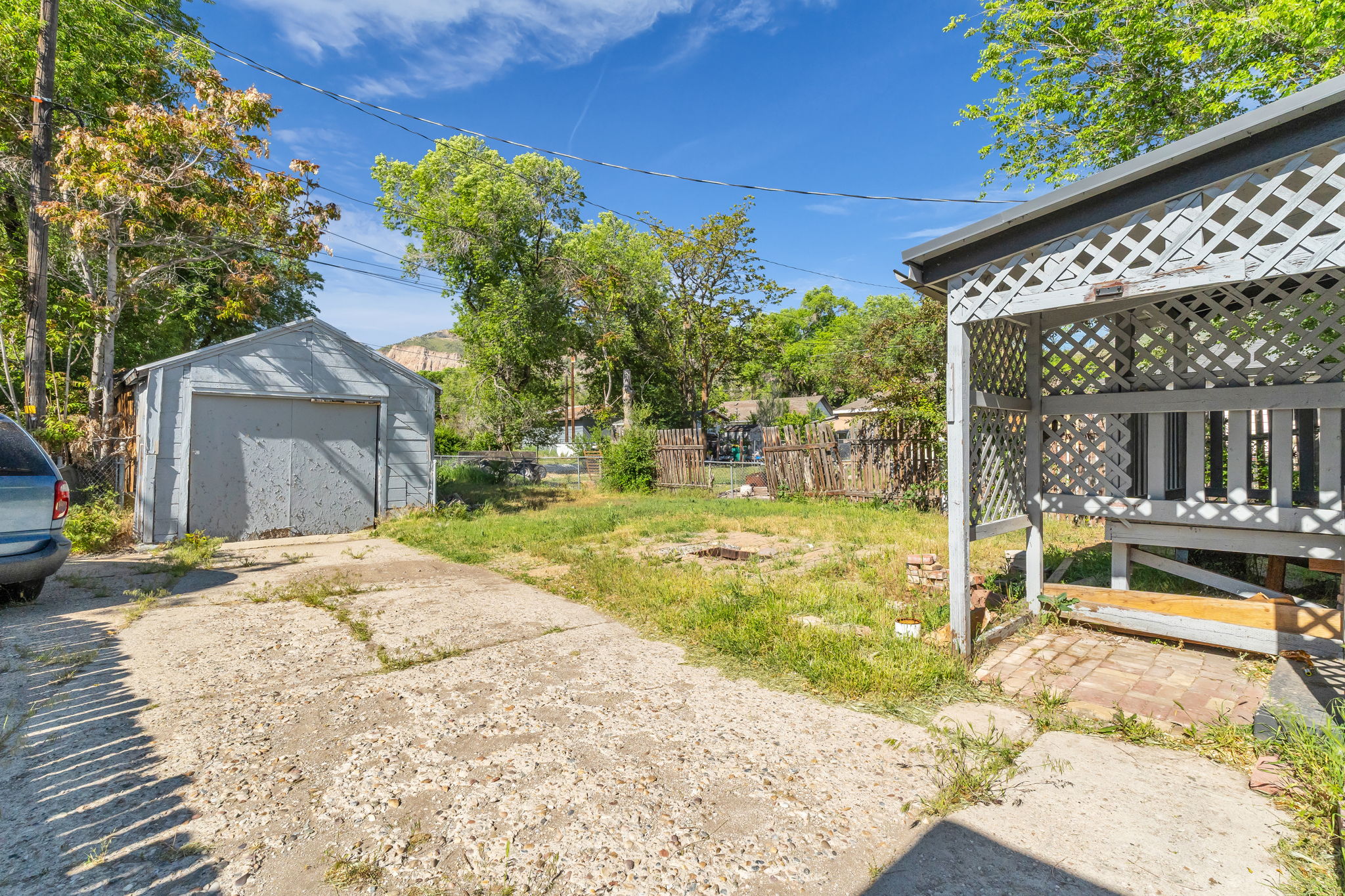 Detached garage structure with a concrete driveway, a lattice-paneled gazebo, and a partially fenced yard