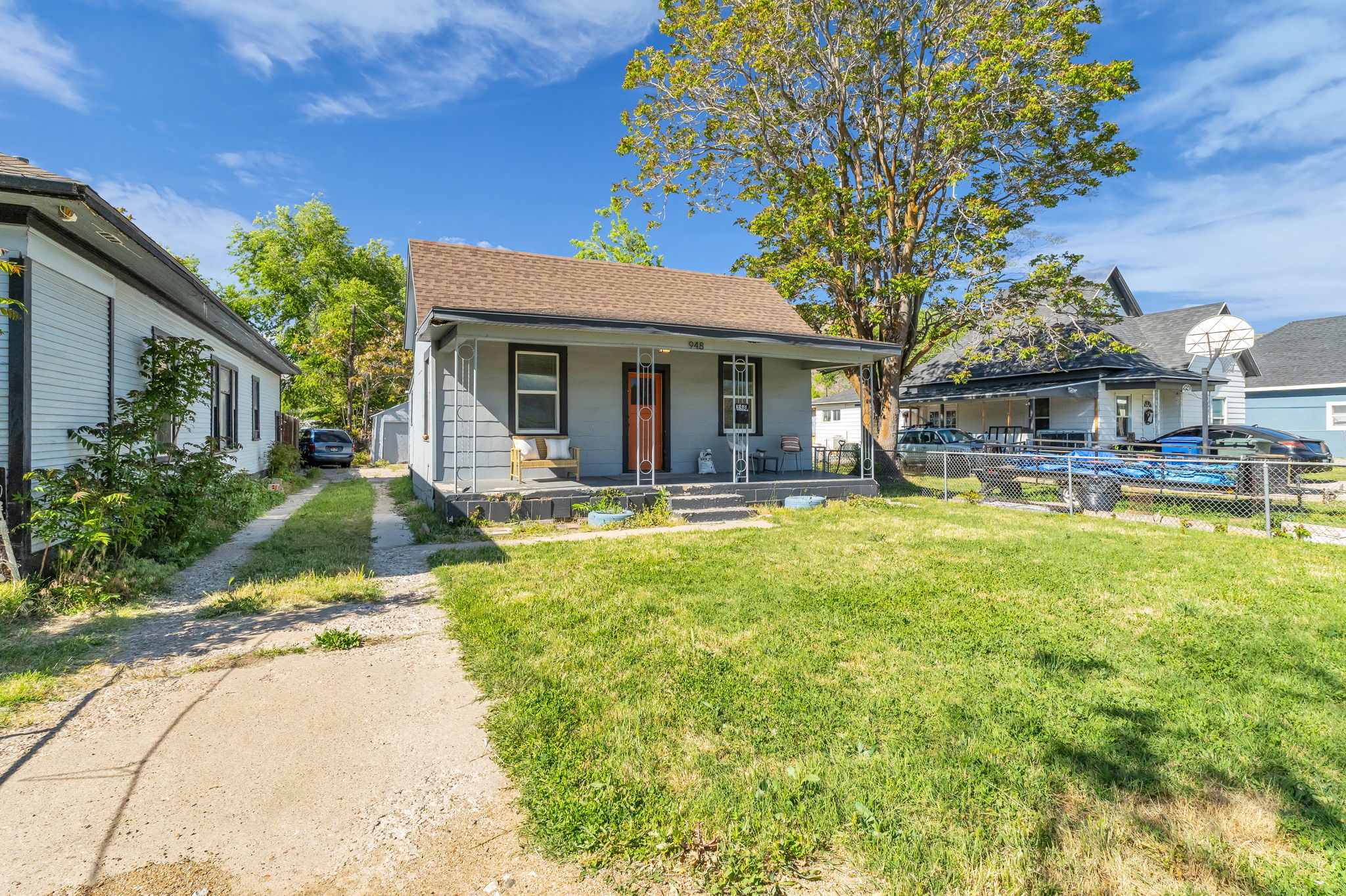 Single-story residence featuring a covered front porch with a wood bench, a gravel driveway, and a front lawn