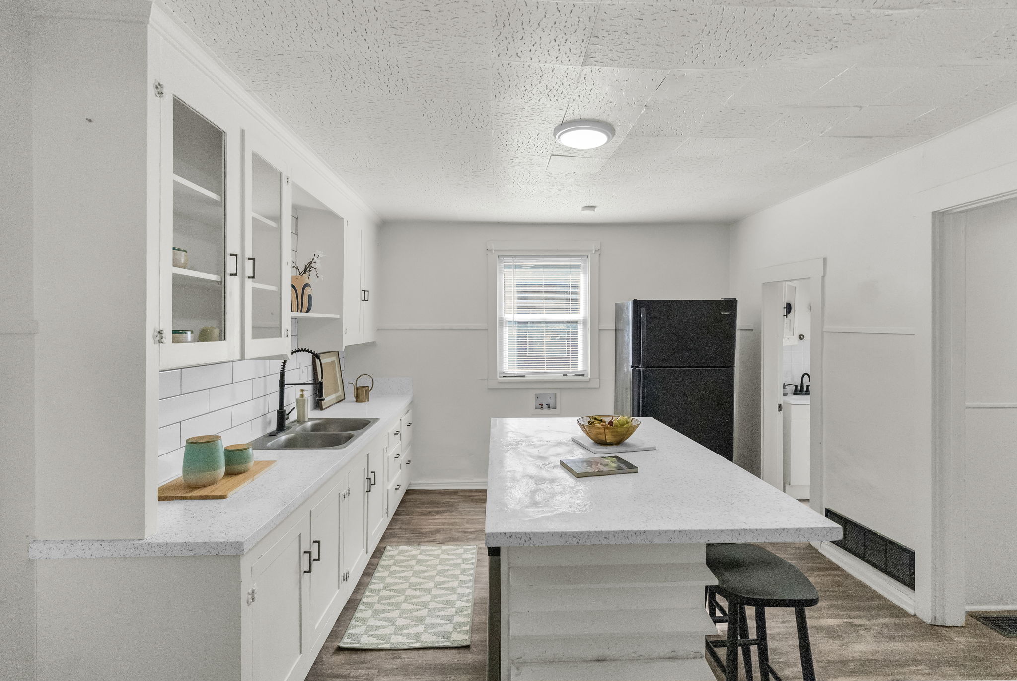 Kitchen with white cabinetry, glass-front upper cabinets, and a subway tile backsplash