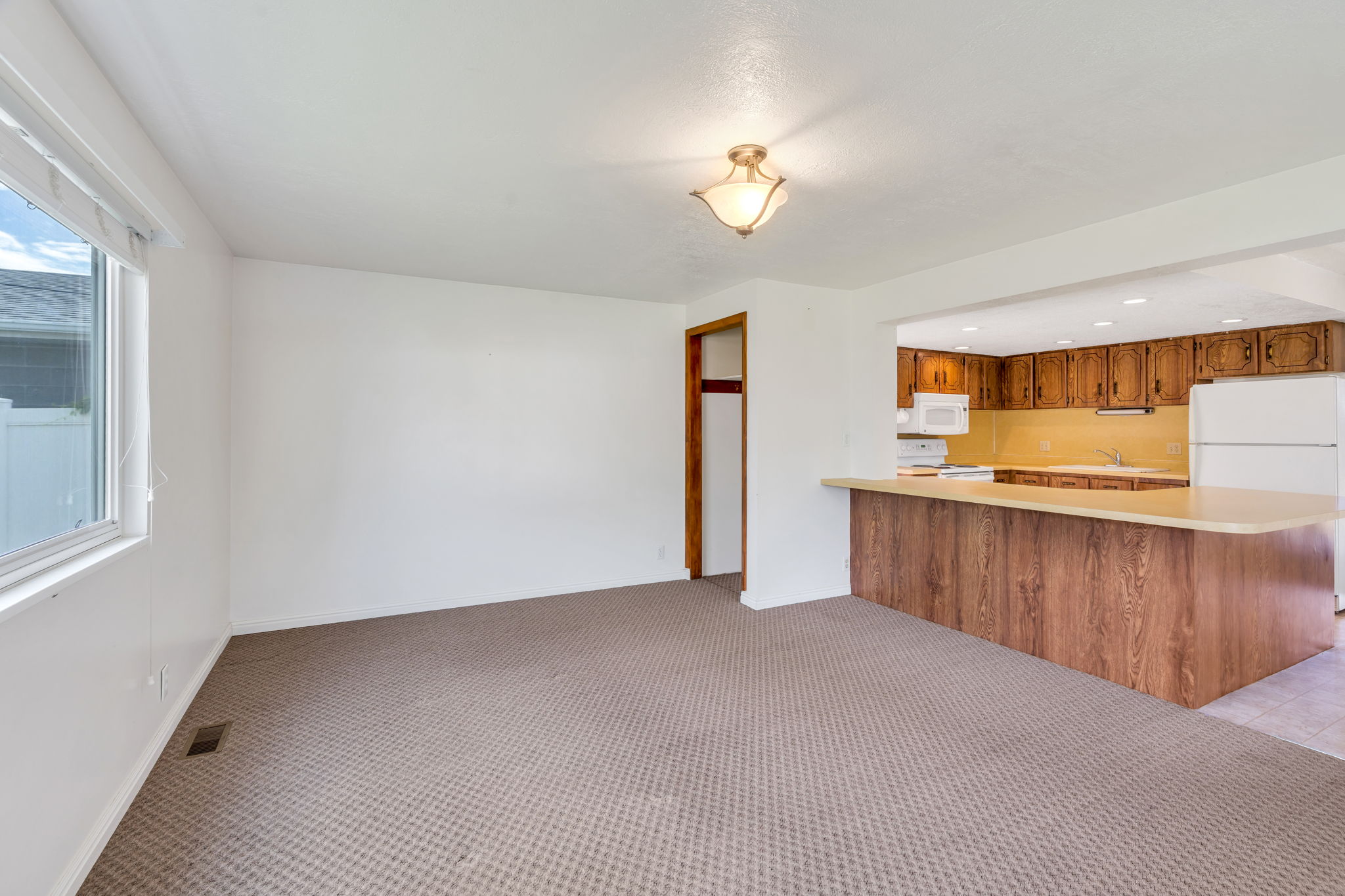 Open-concept living area featuring a breakfast bar with wood-finish paneling, wood cabinetry, and a window
