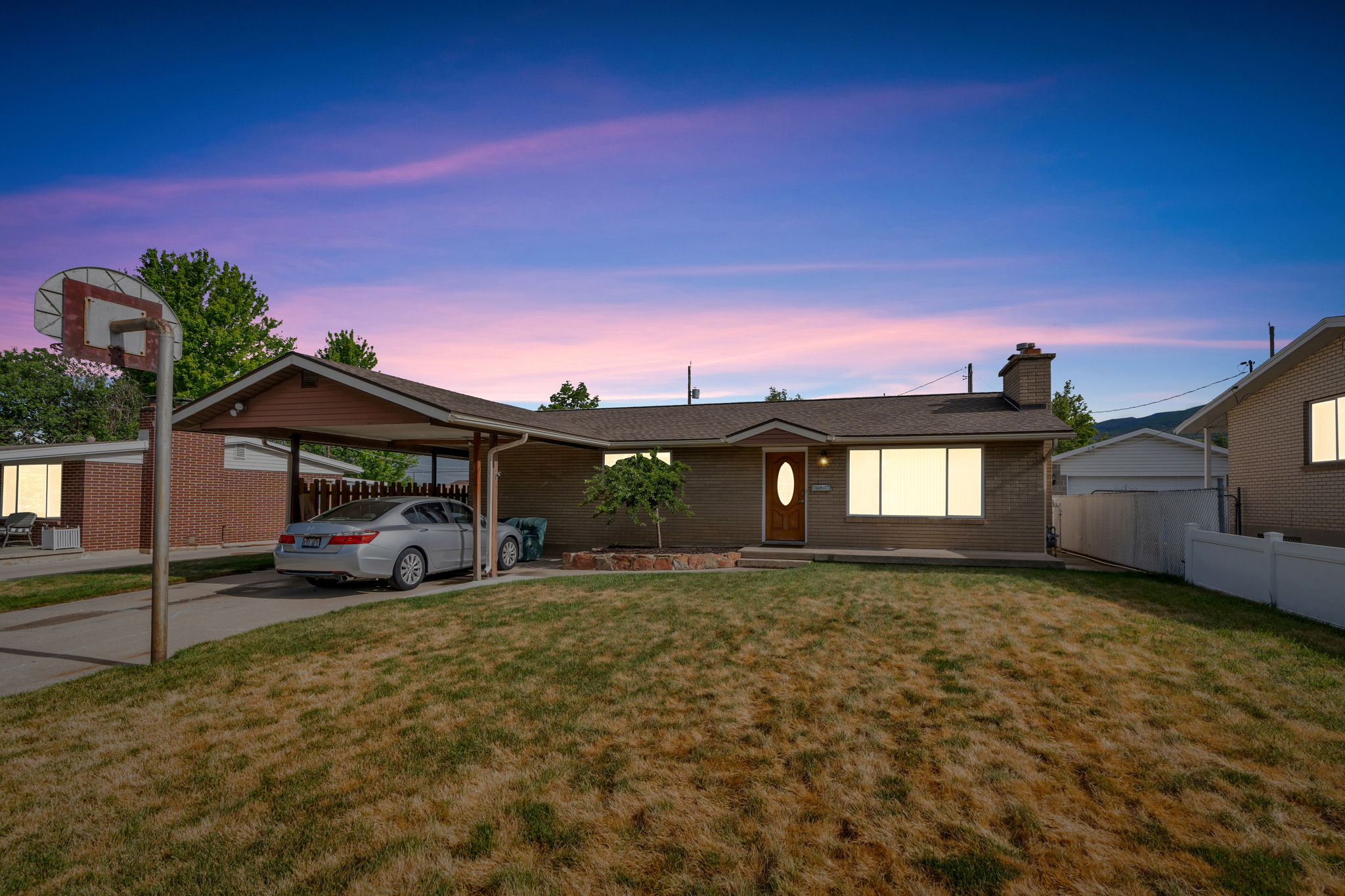 Brick exterior residence featuring a carport, front yard, and a paved driveway