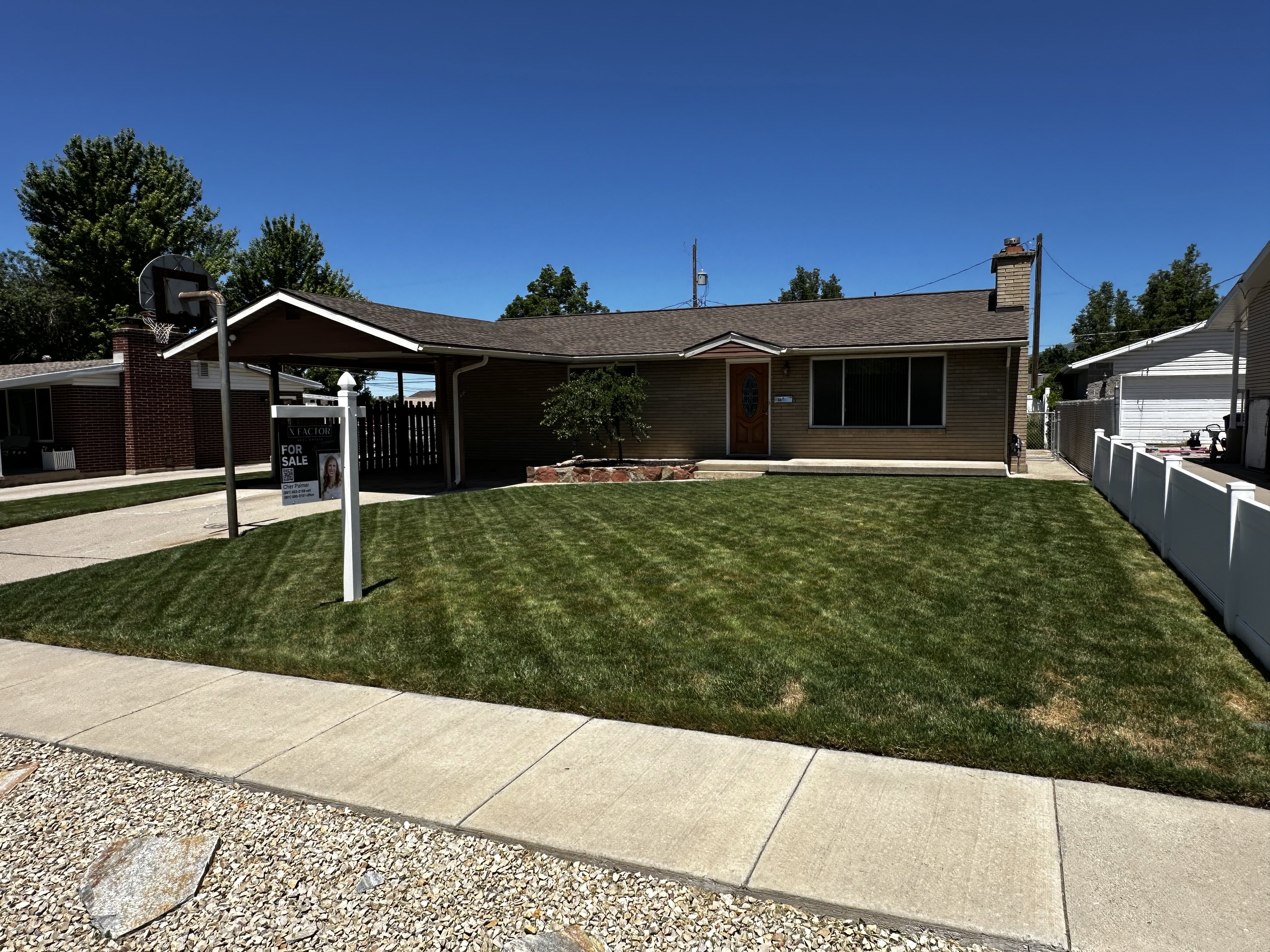 Single-story residence featuring a covered carport, mature front lawn, and concrete driveway