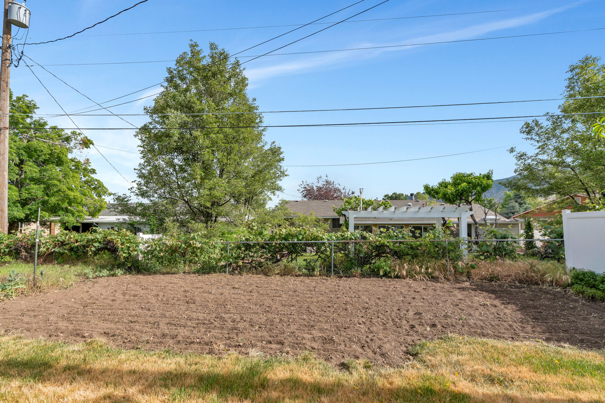 Expansive tilled garden space bordered by a chain link fence