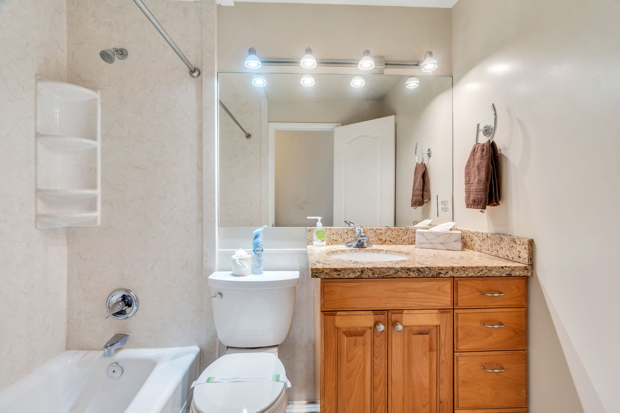 Bathroom featuring a granite-style countertop, wood-finish vanity, and a shower-tub combination with tiled walls