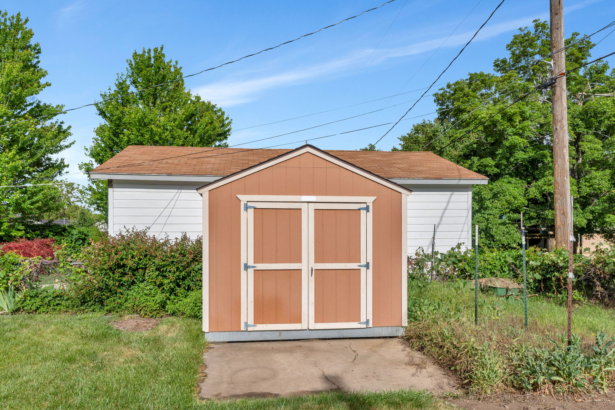 Freestanding shed featuring double doors and a pitched roof, situated on a concrete pad