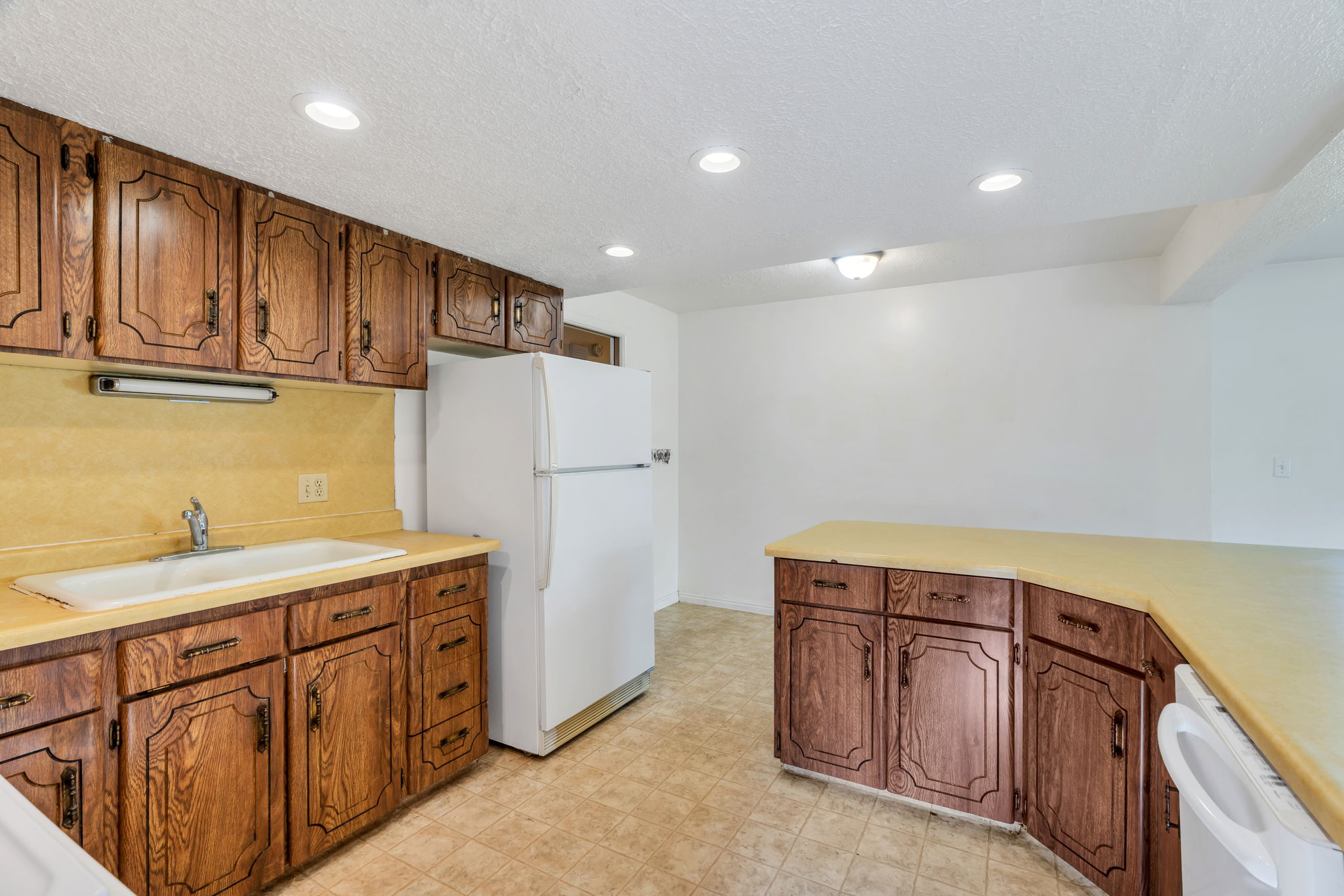 Kitchen featuring wood cabinetry, light-toned countertops, a built-in sink