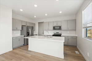 **Disclaimer**  Interior package may vary. Open-concept kitchen featuring an expansive center island, light gray cabinetry, white countertops, stainless steel appliances, and wood-finish flooring