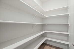 **Disclaimer**  Interior package may vary. Spacious pantry featuring multiple tiers of white shelving, L-shaped lower shelving, and wood-finish flooring