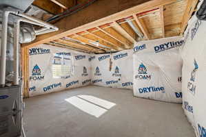 Unfinished basement space featuring exposed wood joists, a concrete floor, and installed insulation on perimeter walls