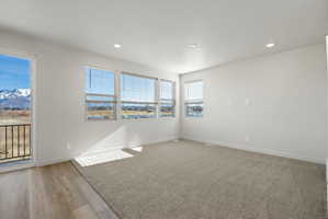 **Disclaimer**  Interior package may vary. Spacious room featuring multiple windows with blinds, light gray carpeting, and wood-finish flooring