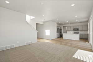 **Disclaimer**  Interior package may vary. Open-concept living space featuring recessed lighting, a carpeted area, and wood-finish flooring