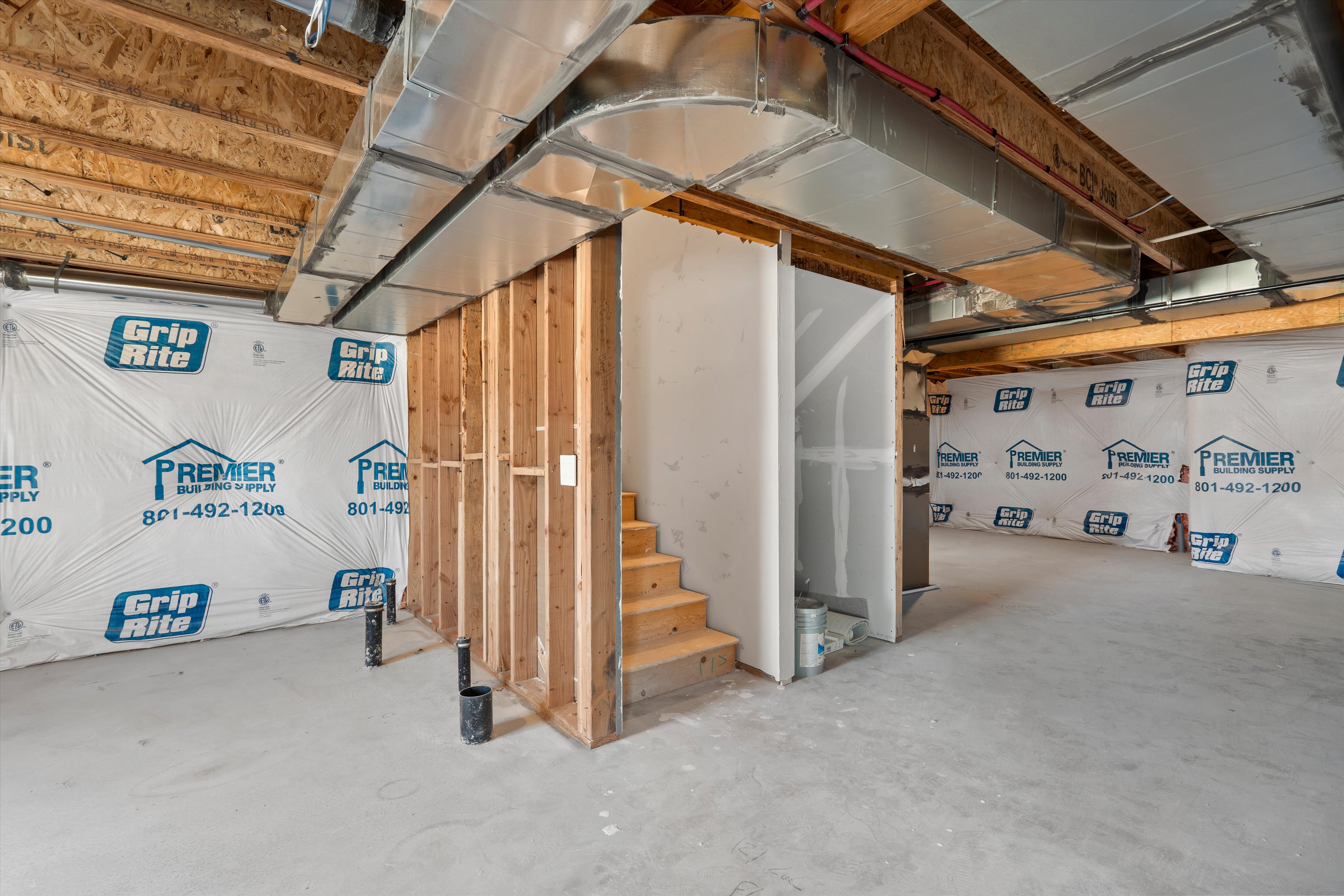 Unfinished basement featuring exposed wood framing, concrete flooring, and an open stairwell