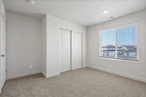 **Disclaimer**  Interior package may vary. Neutral-toned room featuring a large window with horizontal blinds, recessed lighting, and soft carpet flooring