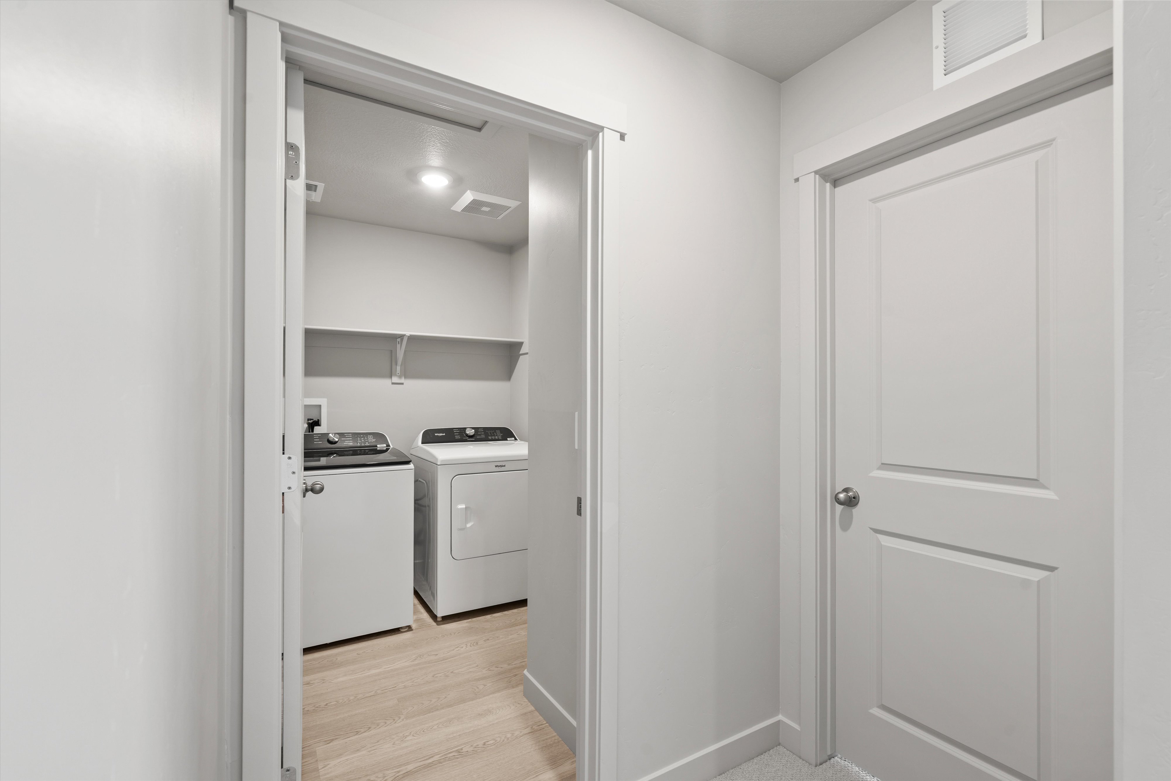 Dedicated laundry area featuring wood-finish flooring, built-in shelving, and recessed lighting