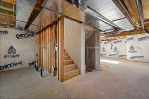 Unfinished basement space featuring exposed wood framing, concrete flooring, and visible ductwork