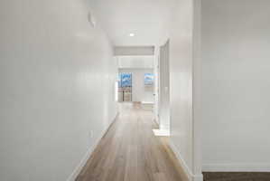 **Disclaimer**  Interior package may vary. Hallway with light wood-finish flooring, recessed ceiling lighting, crisp white walls, and white baseboards