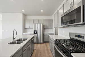 **Disclaimer**  Interior package may vary. Kitchen featuring light gray cabinetry with brushed nickel hardware, white countertops, stainless steel appliances, and wood-finish flooring