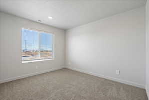 **Disclaimer**  Interior package may vary. Spacious room featuring a large window with horizontal blinds, neutral-toned carpeting, white baseboards, and a recessed ceiling light