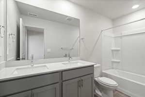 **Disclaimer**  Interior package may vary. Bathroom featuring a dual vanity with light gray cabinetry and white countertops, chrome fixtures, a large wall-mounted mirror, and a white bathtub with an integrated shower