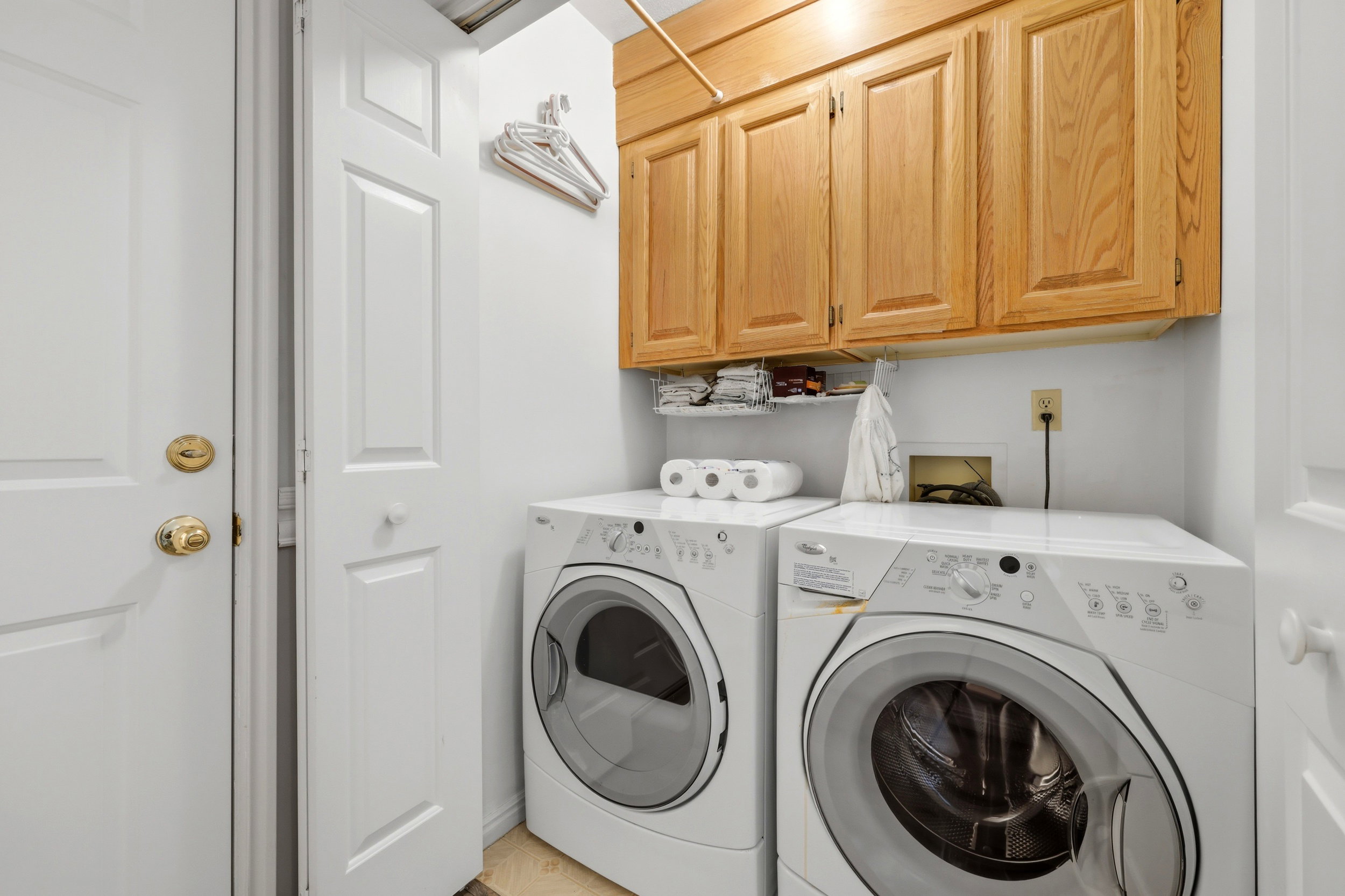 Laundry area featuring wood-finish cabinetry, a built-in hanging rod, and light-toned flooring