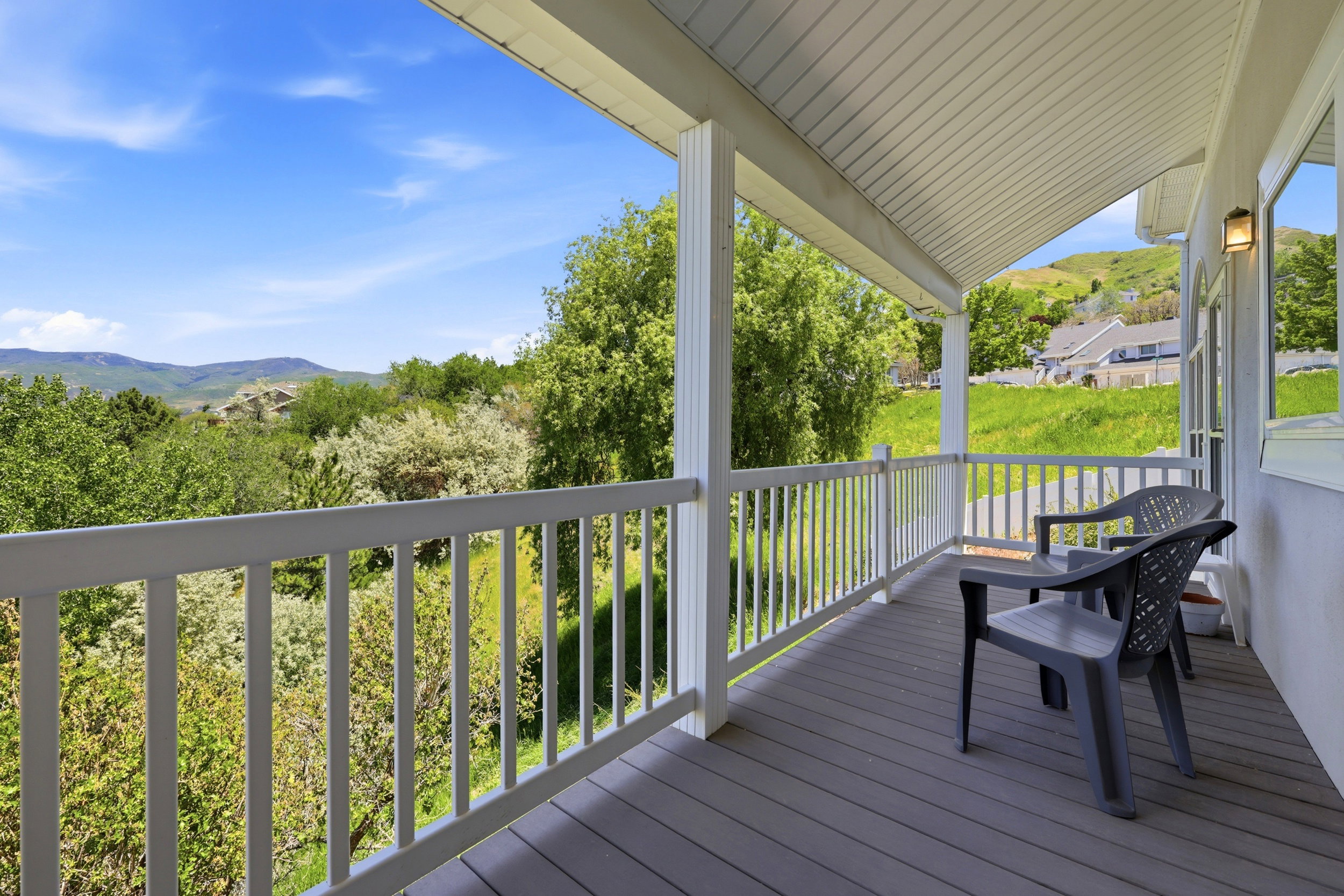 Covered porch featuring a grey deck, white railing, and white support columns