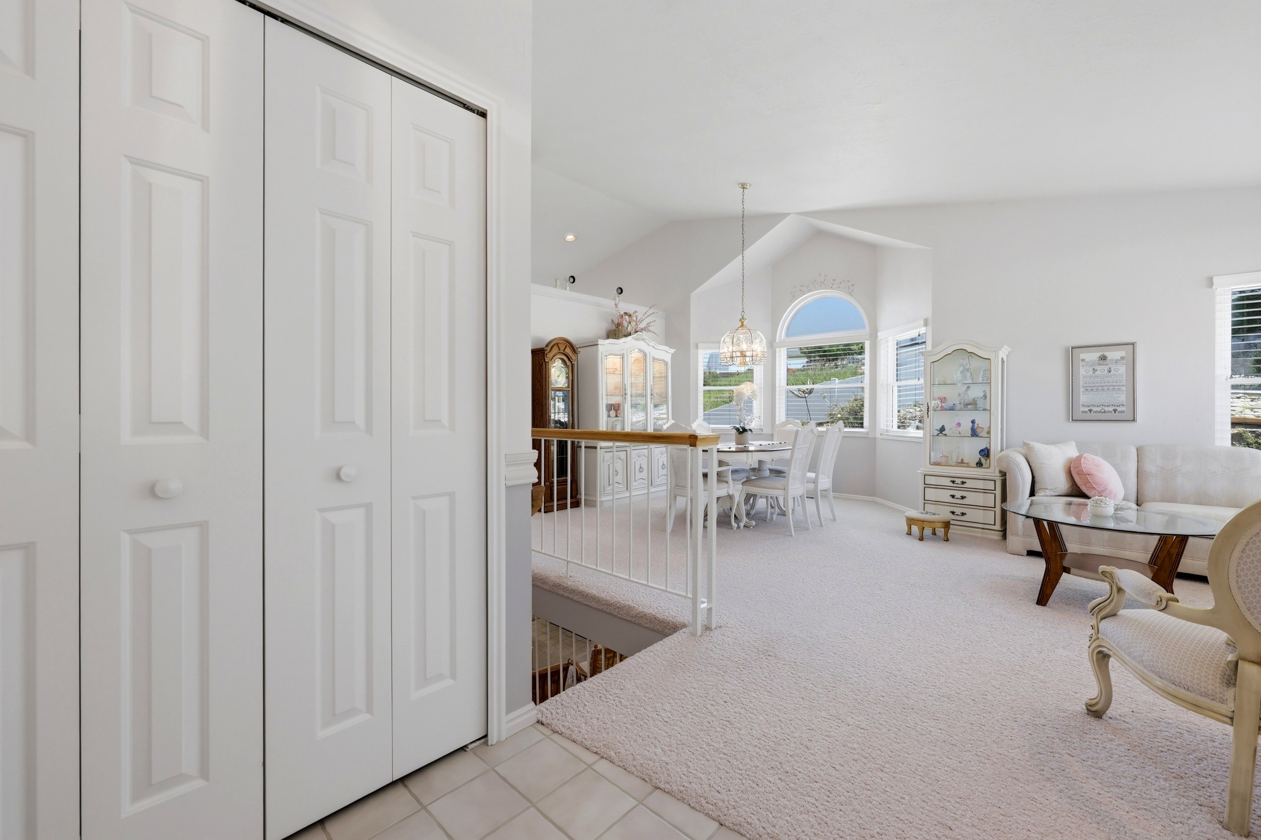 Vaulted ceiling living area featuring multiple windows, including a prominent arched window, and a chandelier-style light fixture