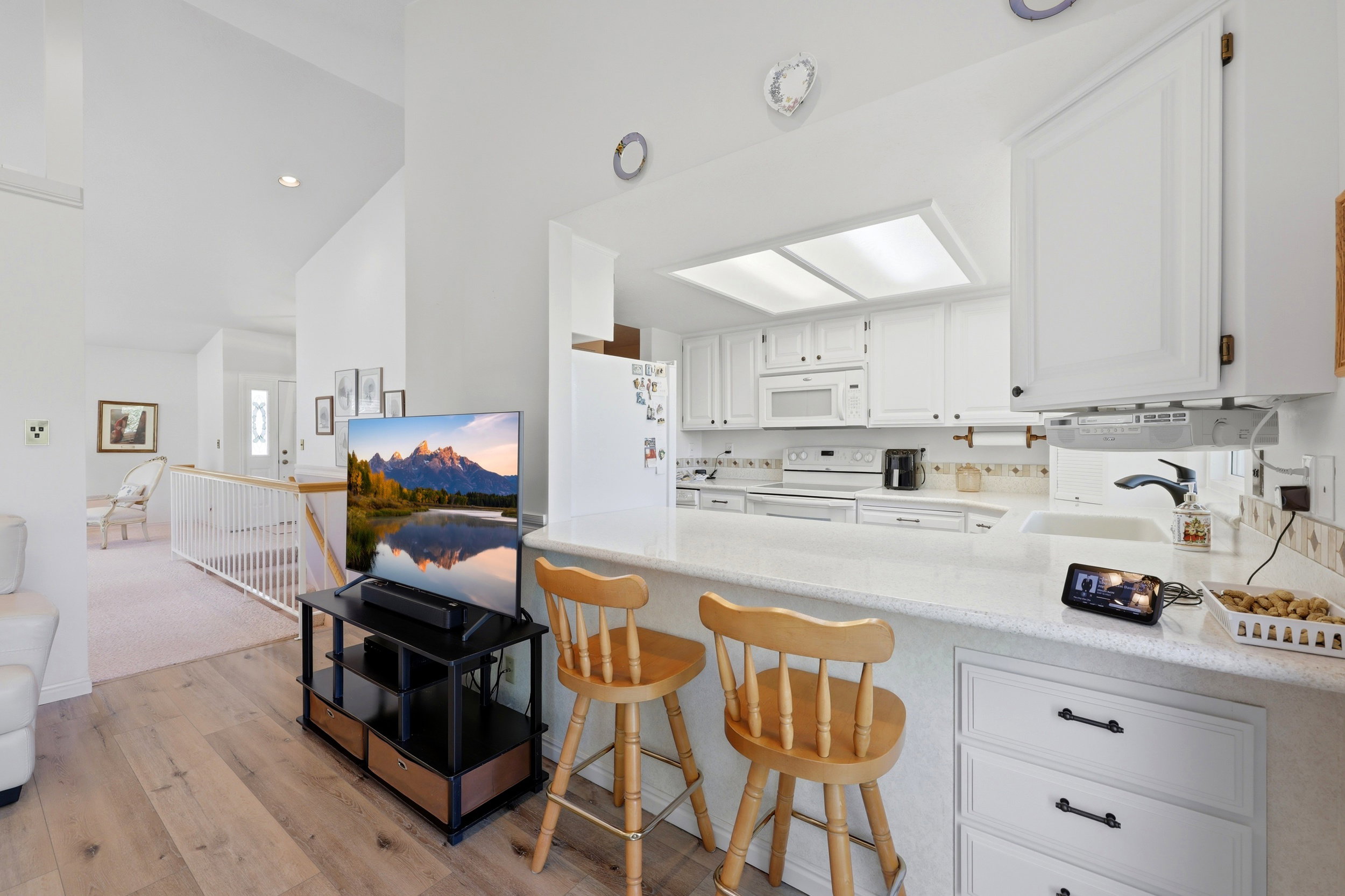 Open-concept kitchen featuring white cabinetry, light countertops, and a white tile backsplash