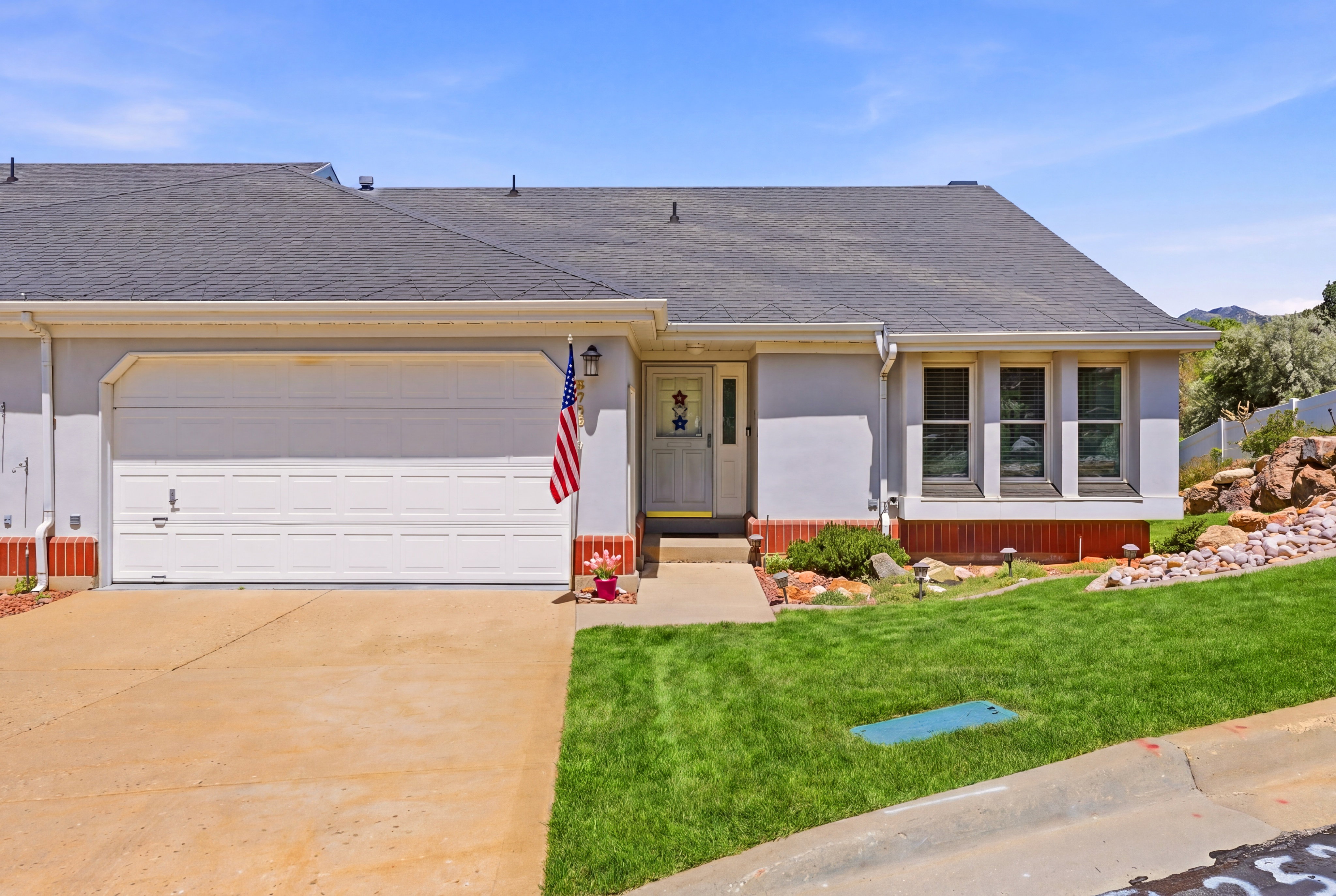 Gray exterior residence with an attached two-car garage, a concrete driveway, and a front walkway leading to the entry
