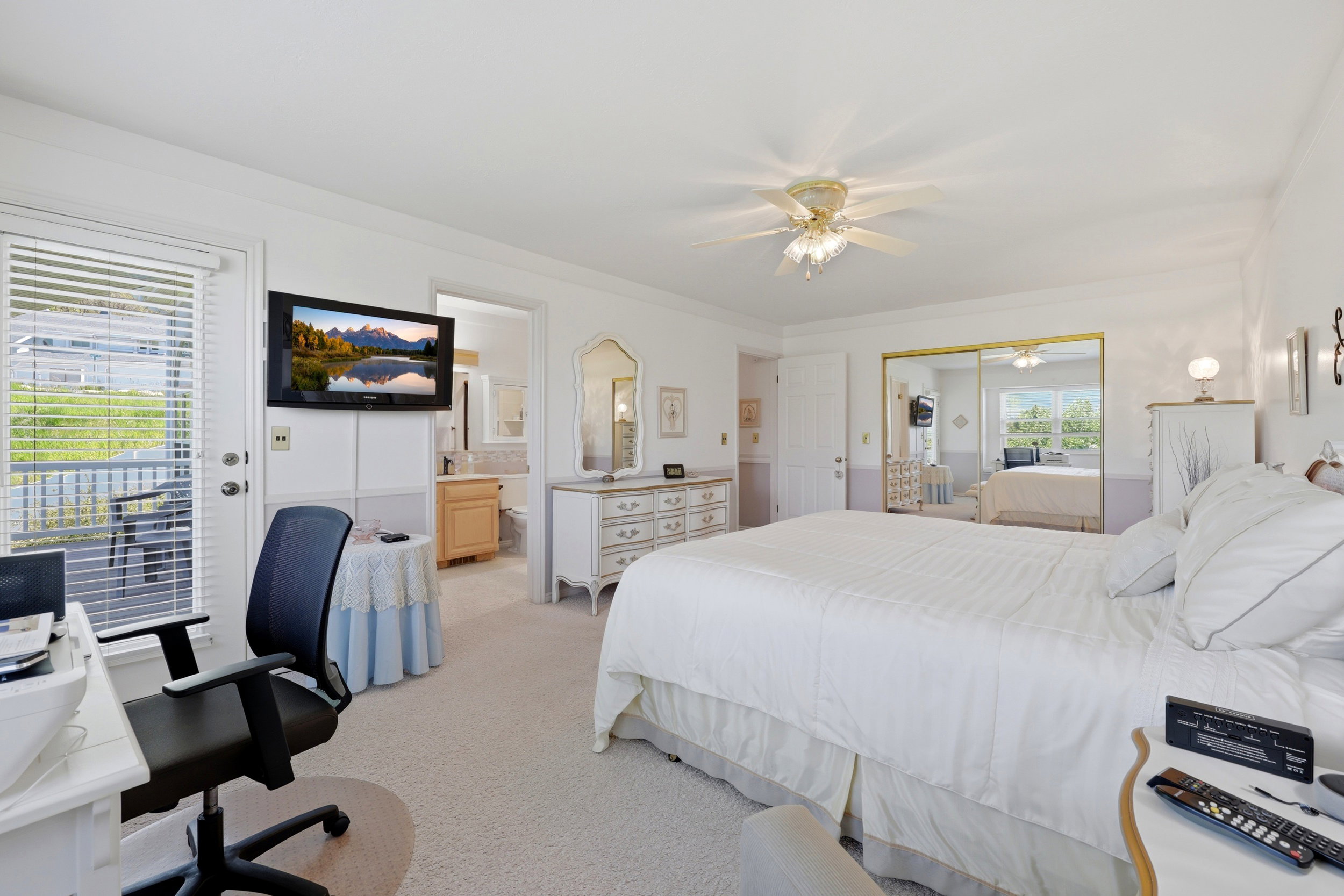 Bedroom featuring a ceiling fan, wall-mounted television, and a glass-paneled door opening to an outdoor area
