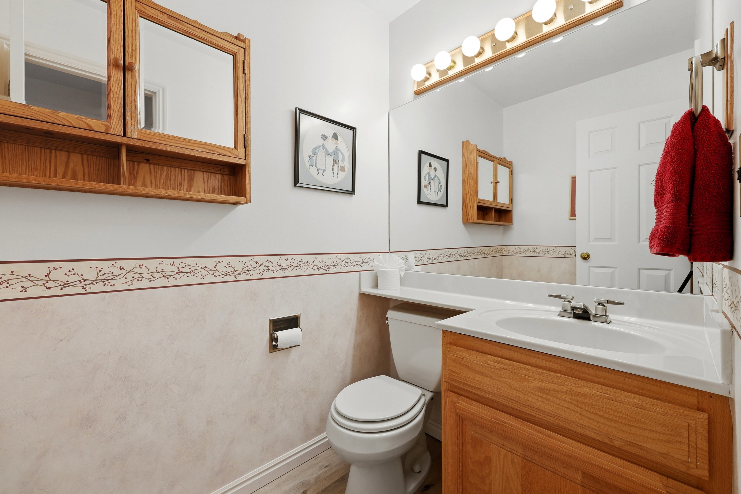 Bathroom featuring a single vanity with a white countertop and integrated sink, a full-width mirror, and a wall-mounted light fixture with five bulbs