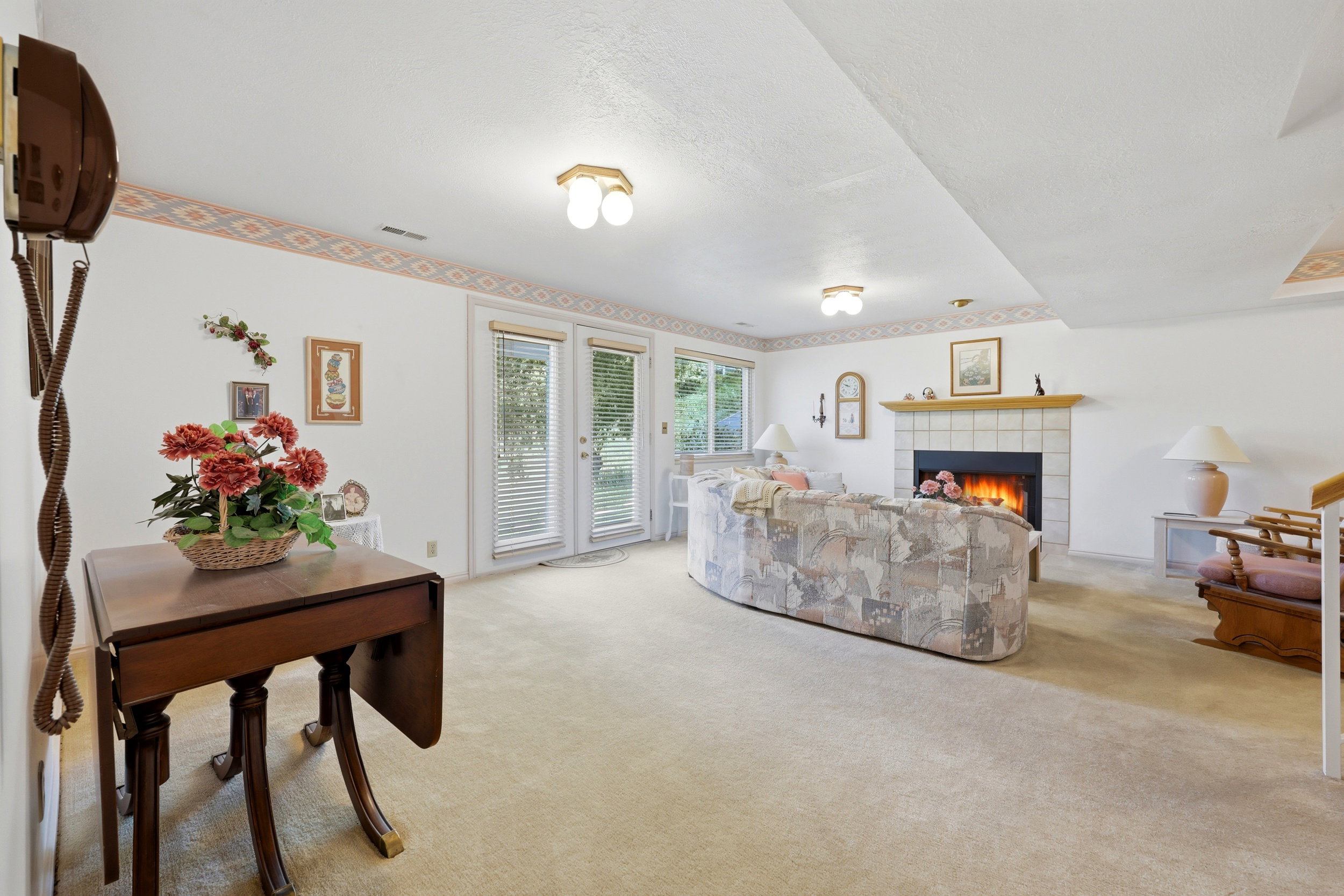 Living area featuring a tiled fireplace with a wood mantel, dual French doors, and ceiling-mounted lighting fixtures