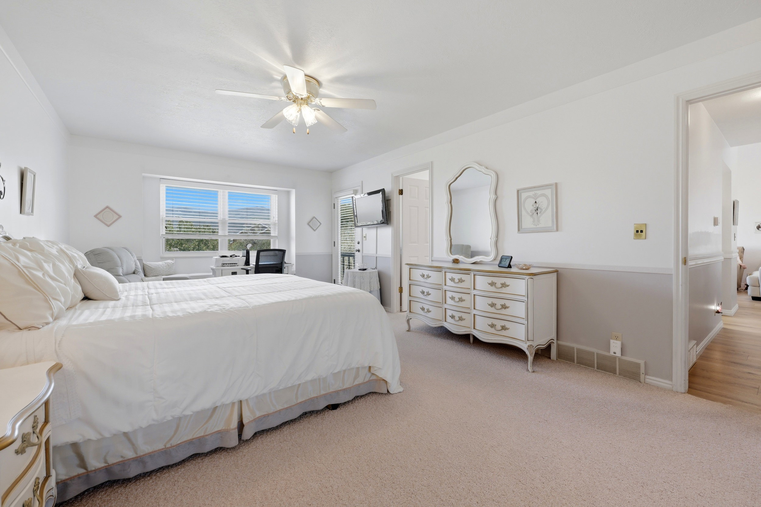 Carpeted room featuring a large window, a ceiling fan with light fixture, and a neutral two-tone wall treatment
