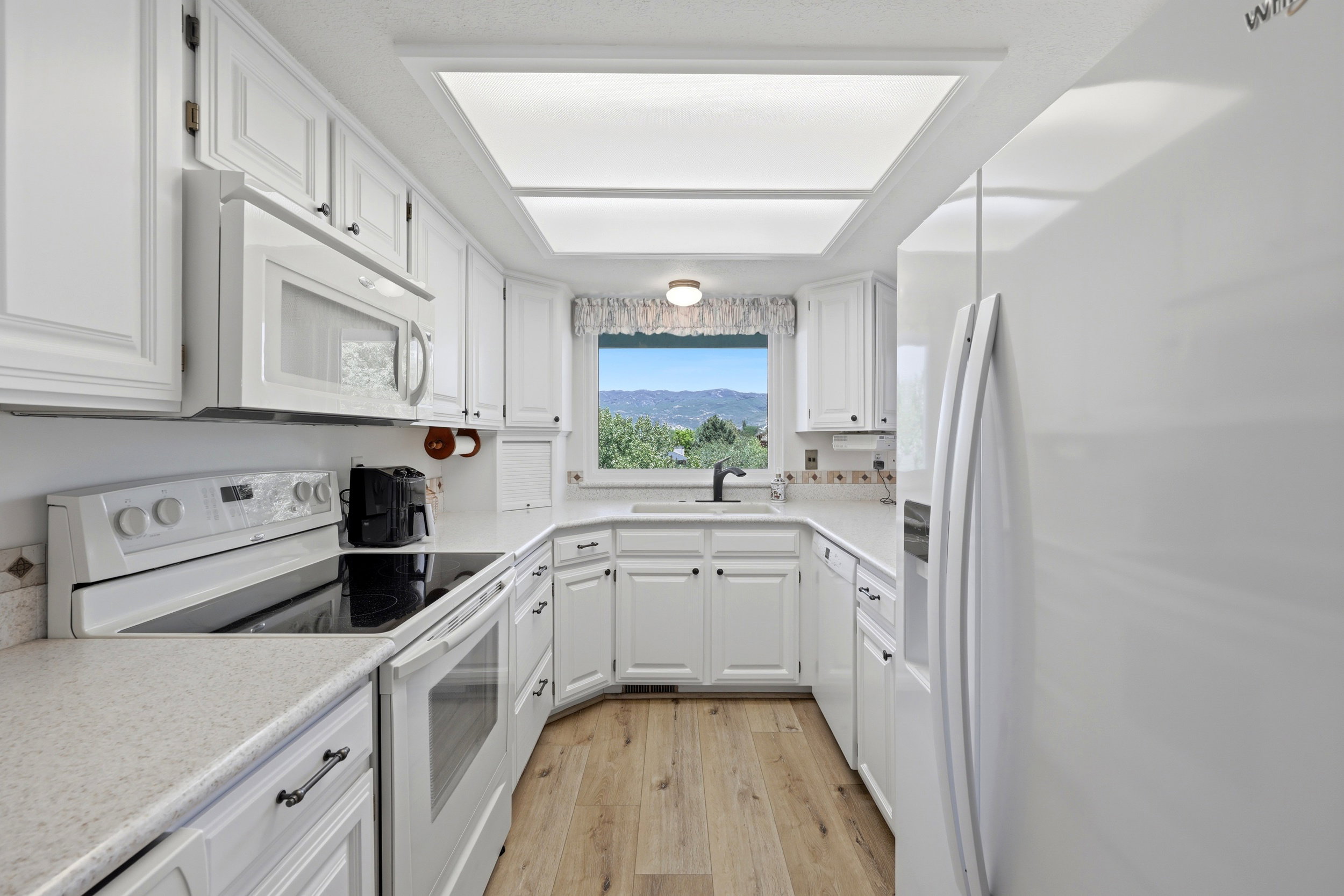 U-shaped kitchen featuring white cabinetry, light-toned countertops, and wood-finish flooring