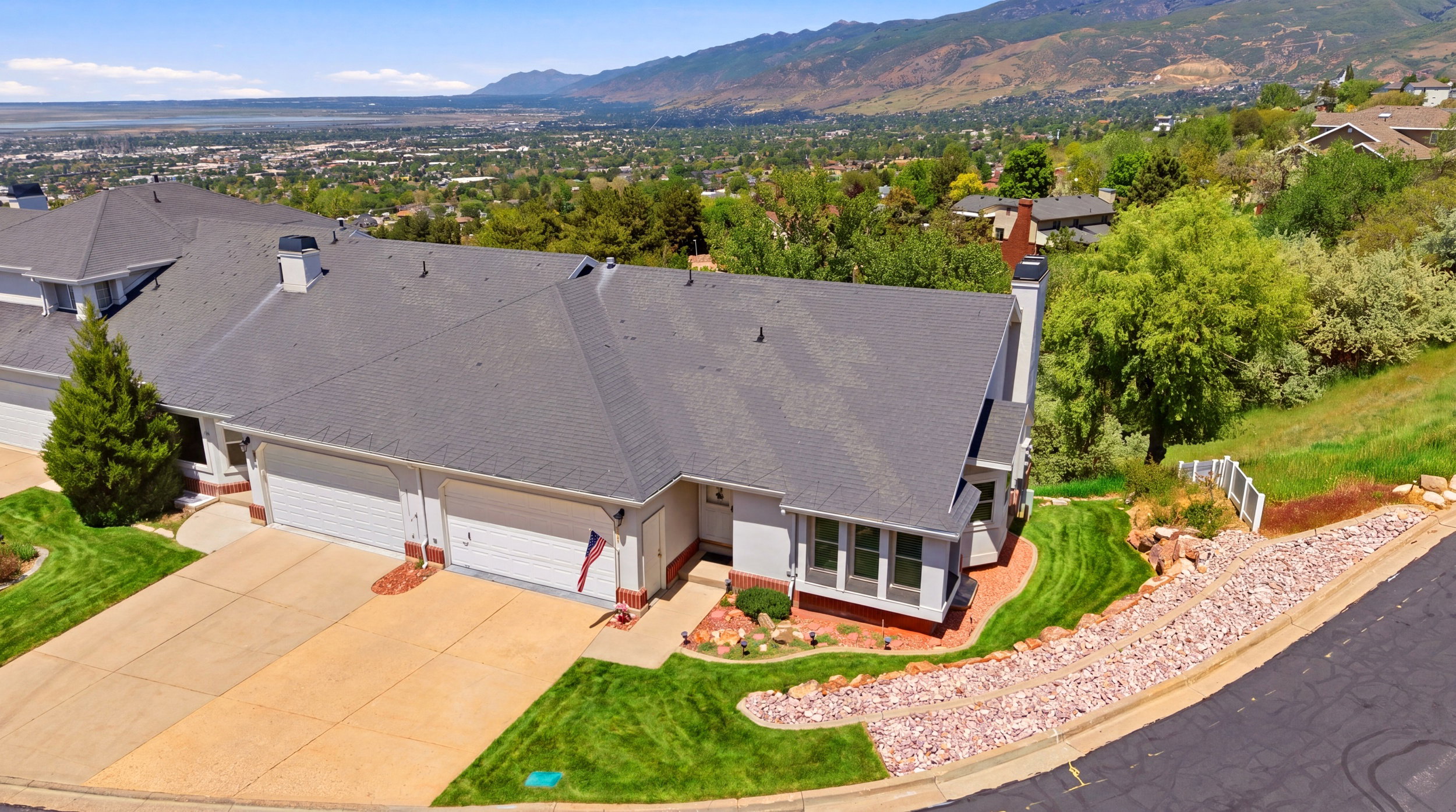Expansive residential property featuring a multiple-car garage, mature landscaping, and a terraced rock garden along the street frontage