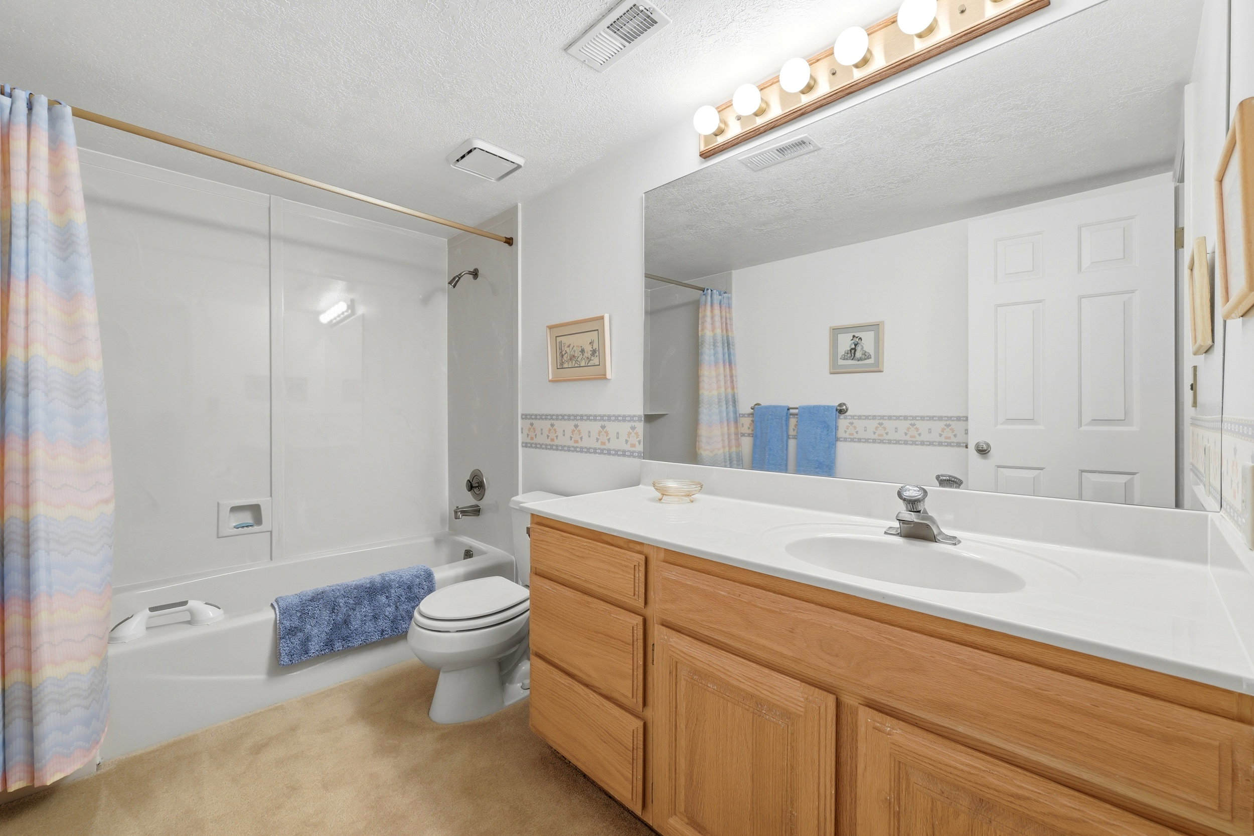 Bathroom featuring a full vanity with wood-finish cabinetry, white countertop, and integrated sink