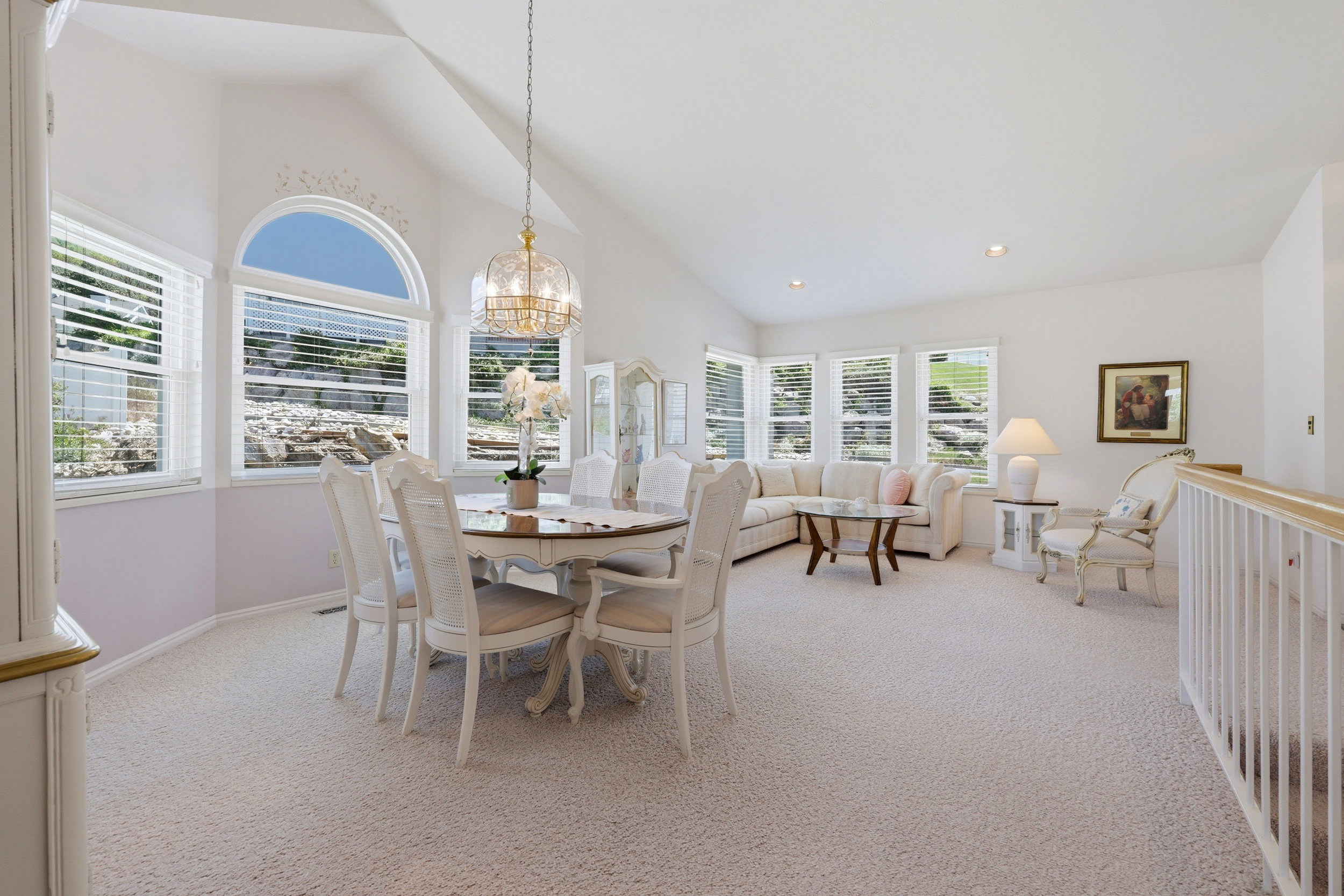 Vaulted ceiling with a central chandelier above a dining area, featuring a series of windows including an arched window