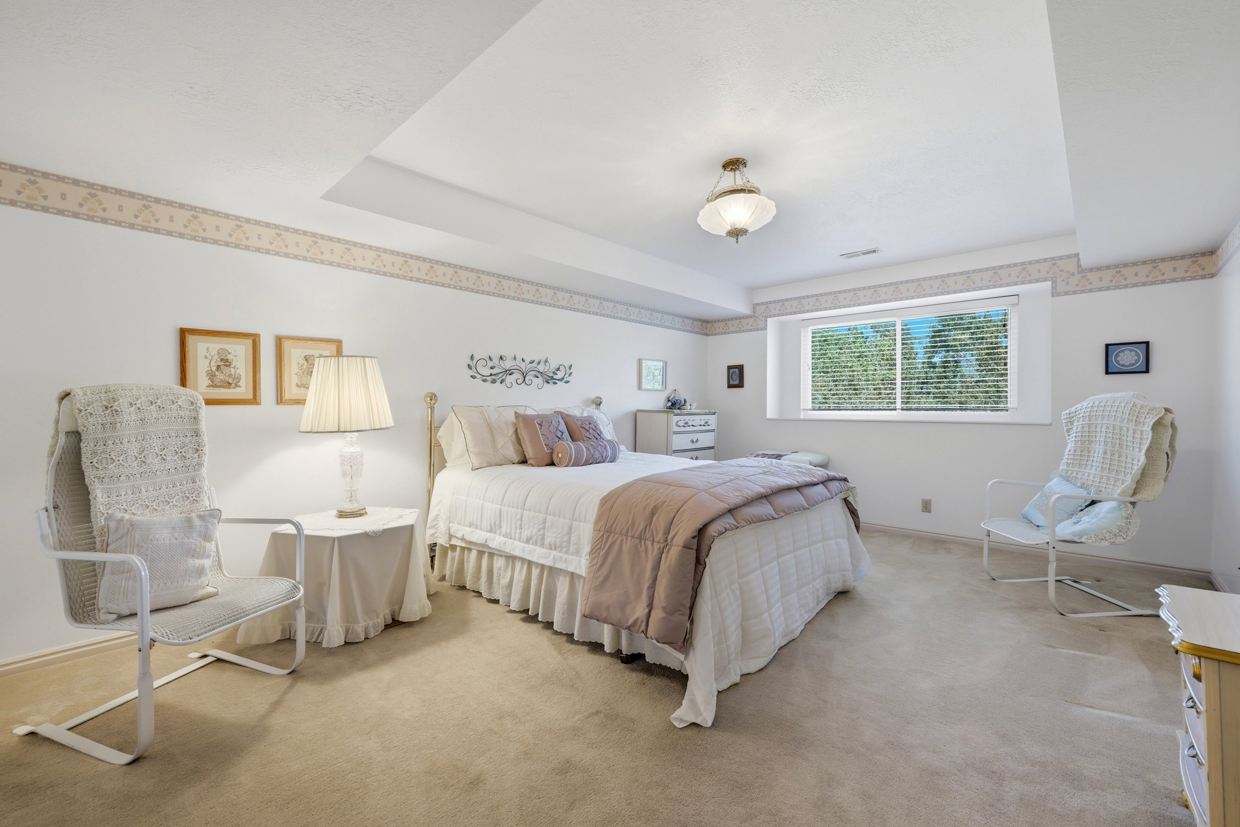Carpeted room featuring a white ceiling with a decorative drop, a single window with horizontal blinds, and a ceiling-mounted light fixture