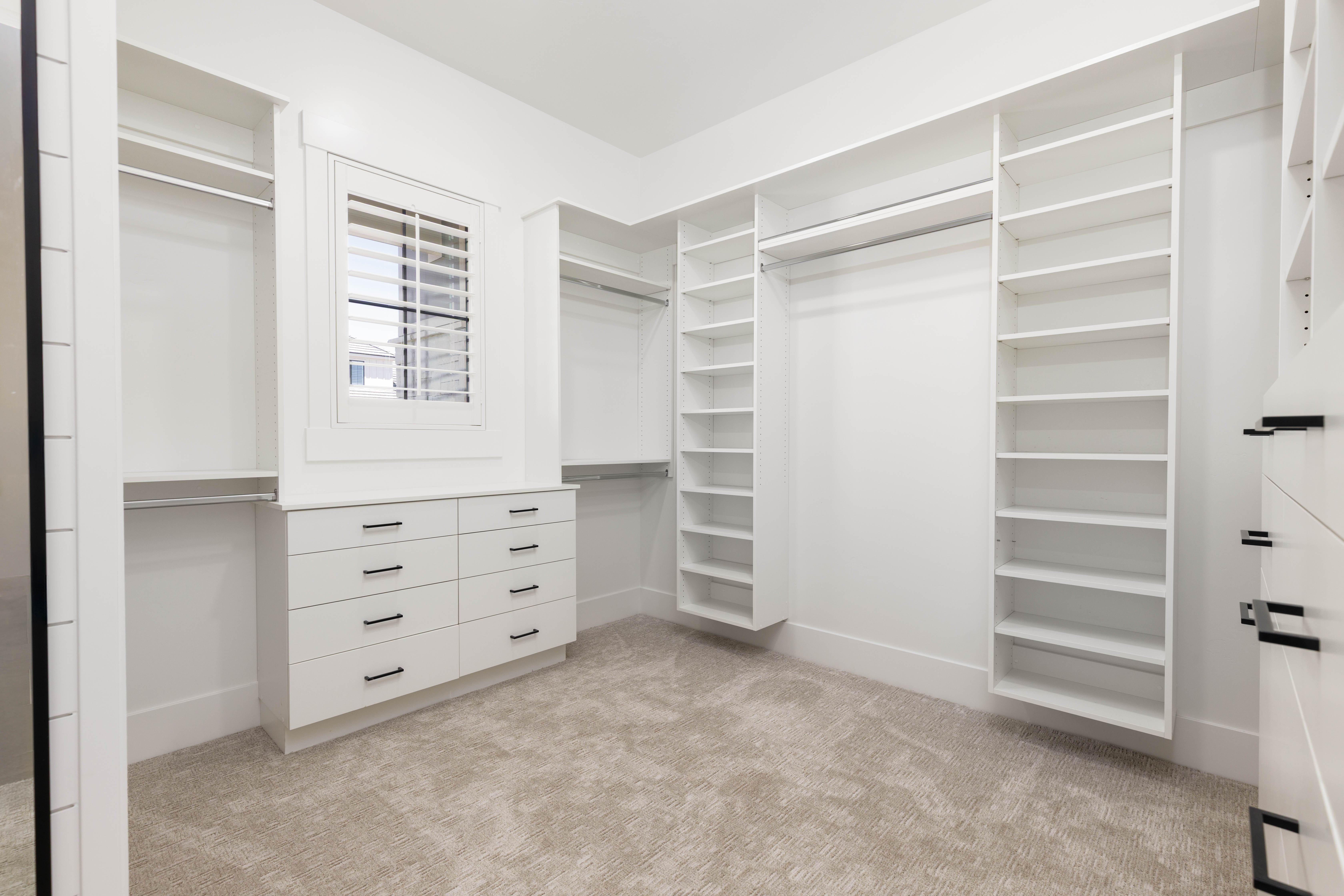 Custom closet system featuring extensive shelving, hanging rods, and built-in drawers with matte black hardware
